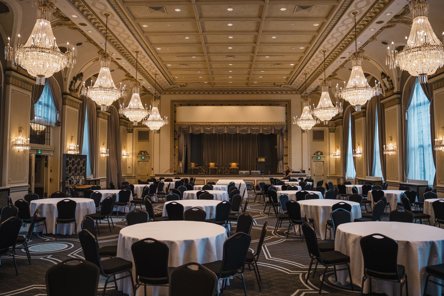 Luxurious empty banquet hall in Québec featuring round tables, elegant chandeliers, and classical architecture.