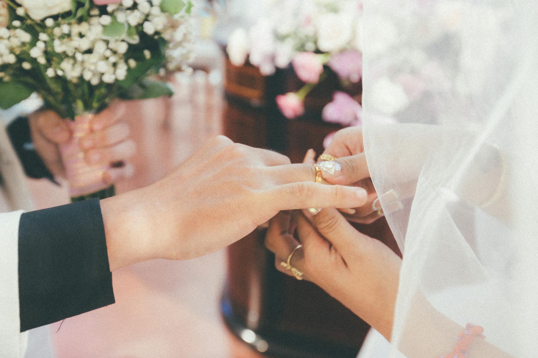 A close-up of a bride and groom exchanging rings during their wedding ceremony, symbolizing love and commitment.