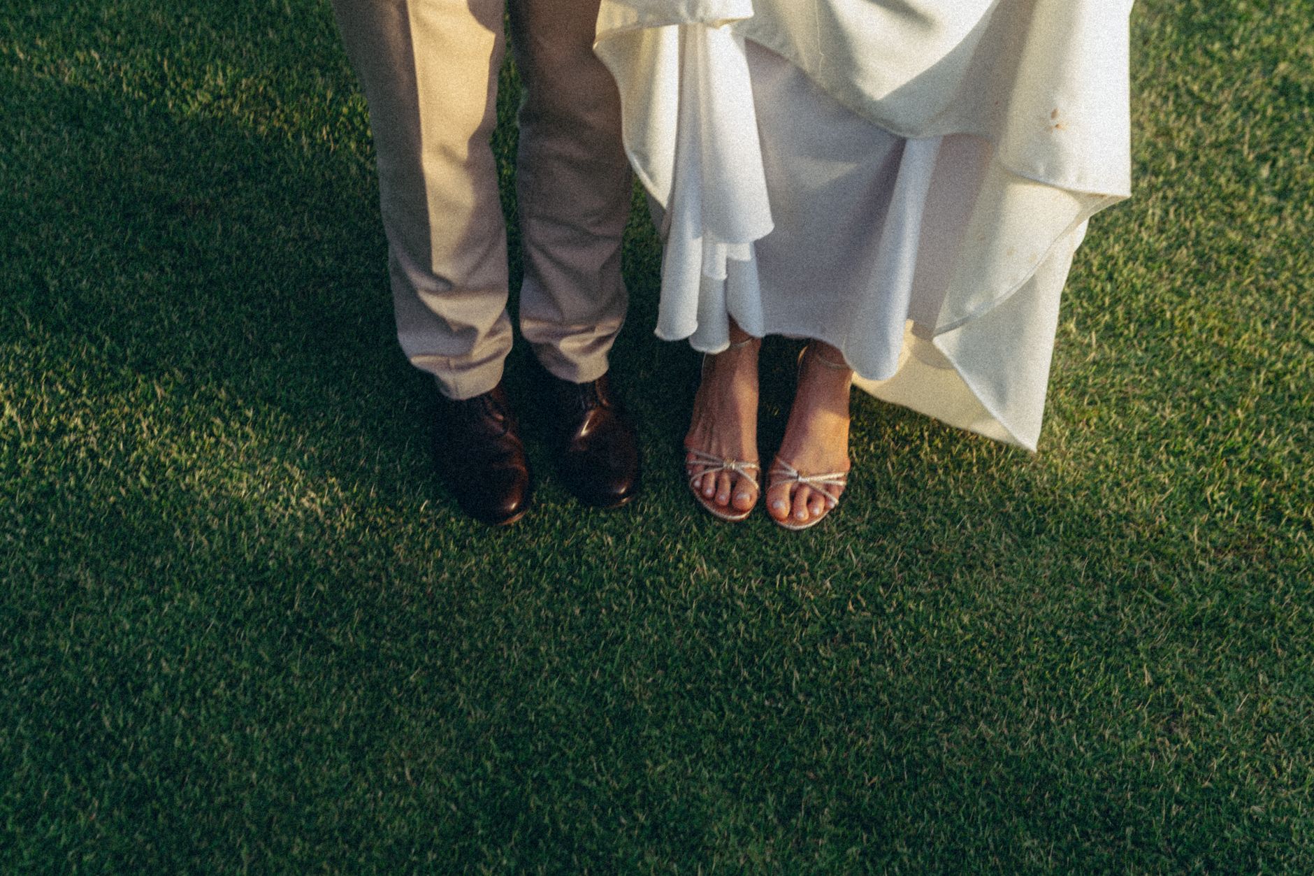 A close-up of a bride and groom's feet on grass, captured during a wedding in Maringá, Brazil.