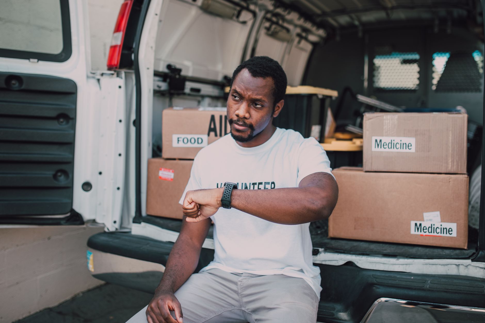 A volunteer organizing aid deliveries including food and medicine from a van.