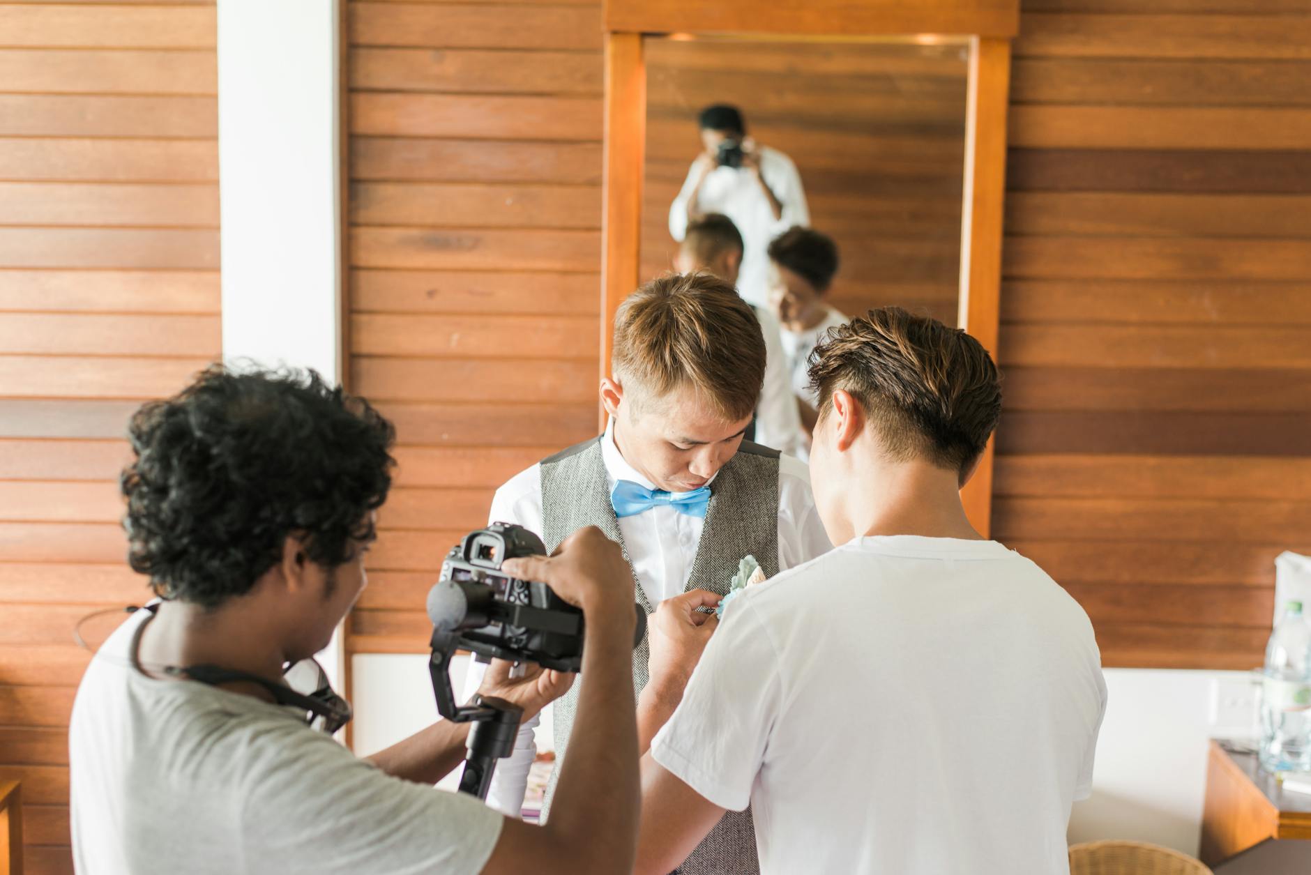 Three men in a dressing room preparing for a wedding photoshoot.