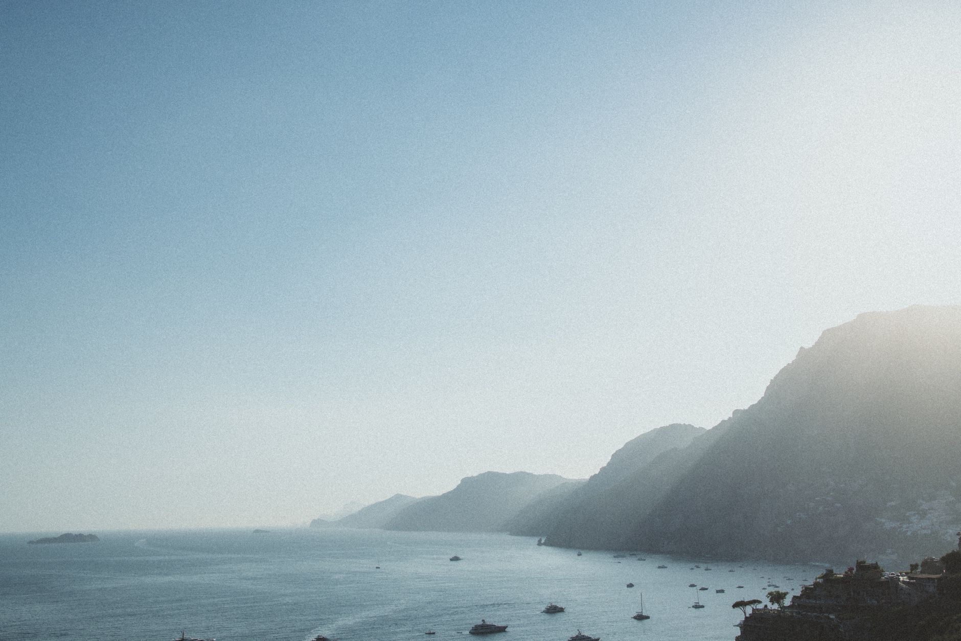 Scenic view of Positano's stunning rocky coastline under bright sunlight, perfect for summer travel inspiration.