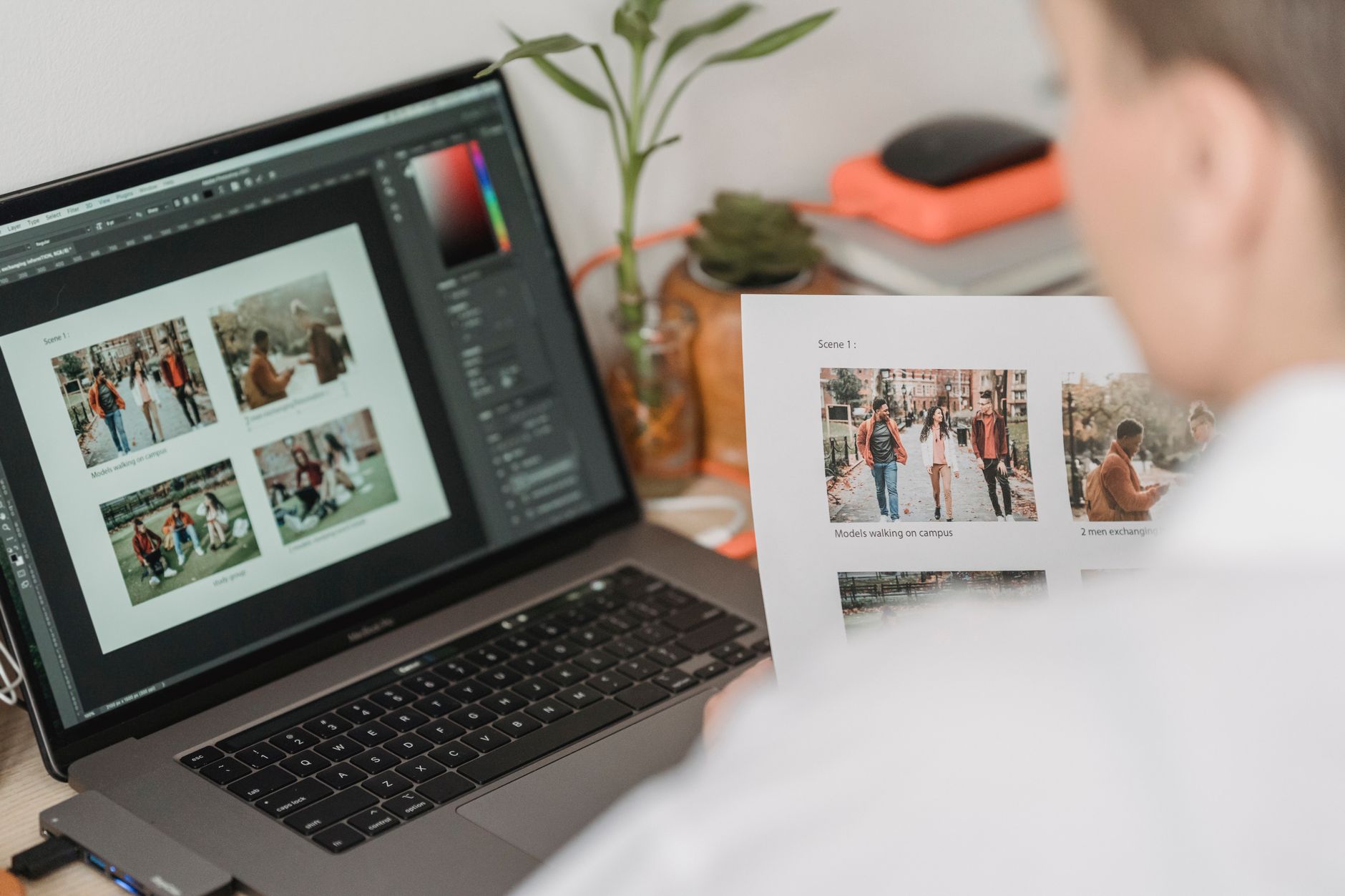 High angle of crop female photographer sitting at table with laptop and printed photoshoot while working remotely