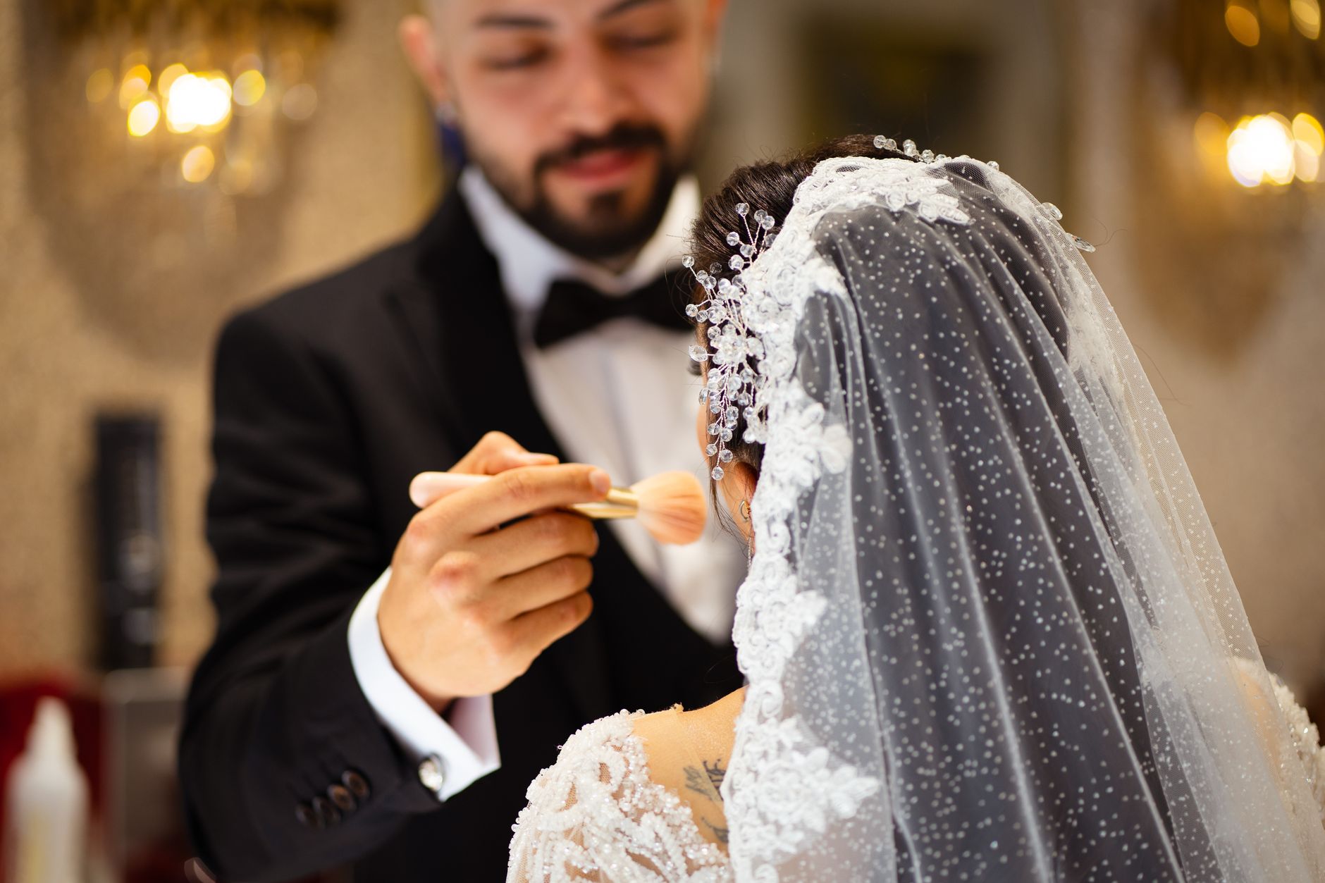 A bride receives makeup touch-up by groom before her wedding ceremony.