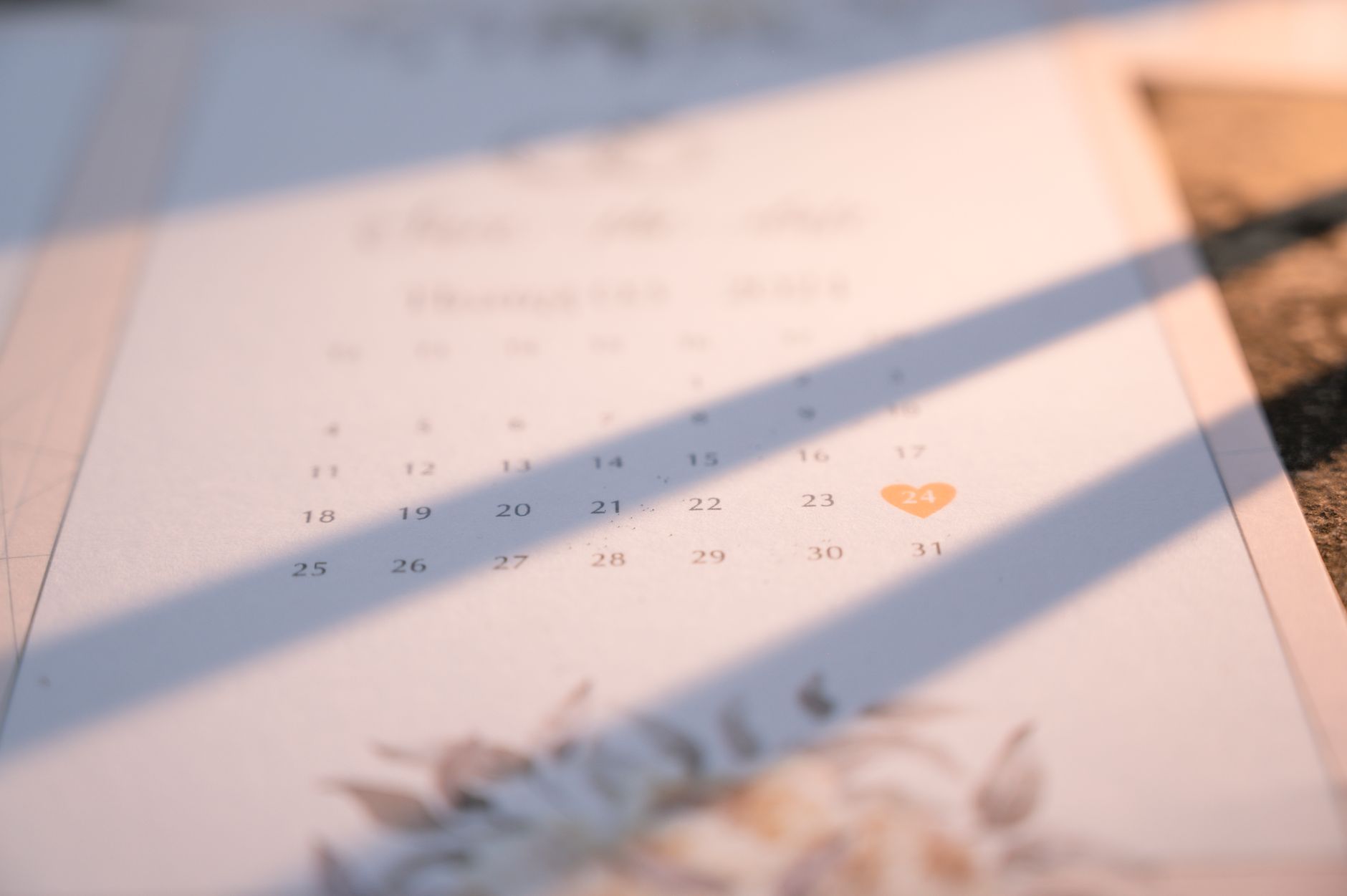 Soft focus on a wedding date marked with a heart on a stylish, floral-themed calendar.