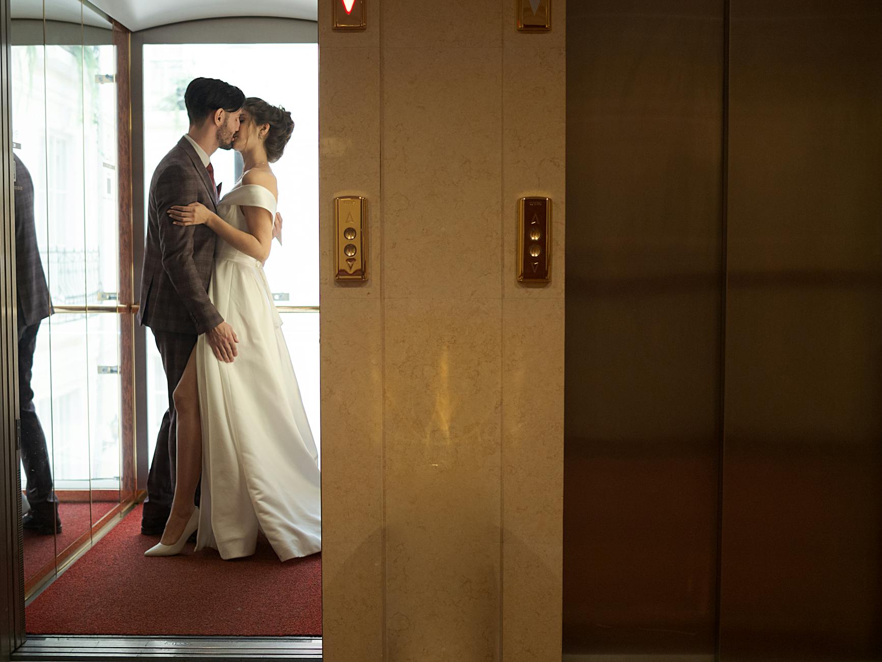 Elegant couple kissing in an elevator, capturing a romantic wedding moment.