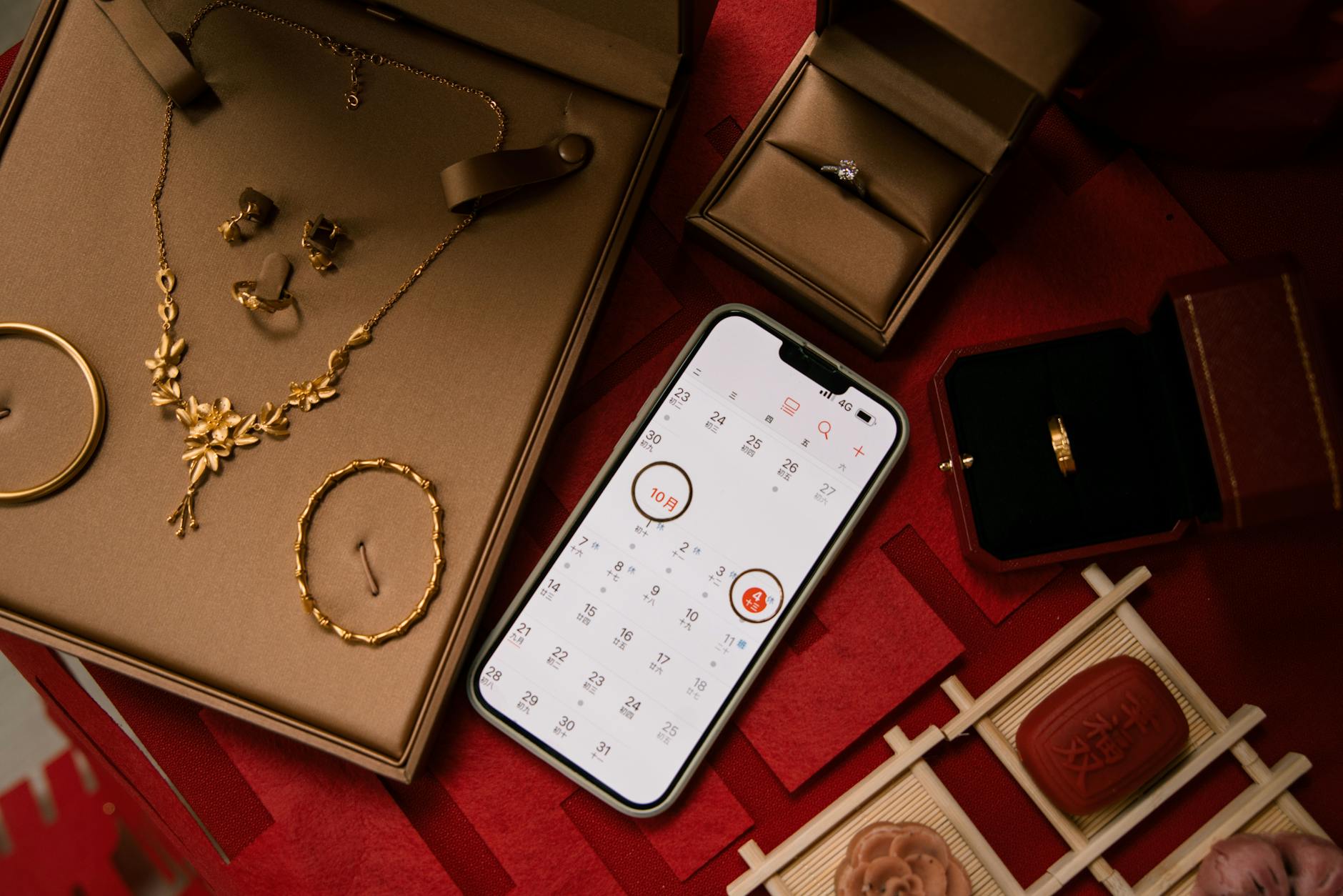 A stylish flat lay featuring gold jewelry alongside a phone displaying a calendar, perfect for special occasion planning.