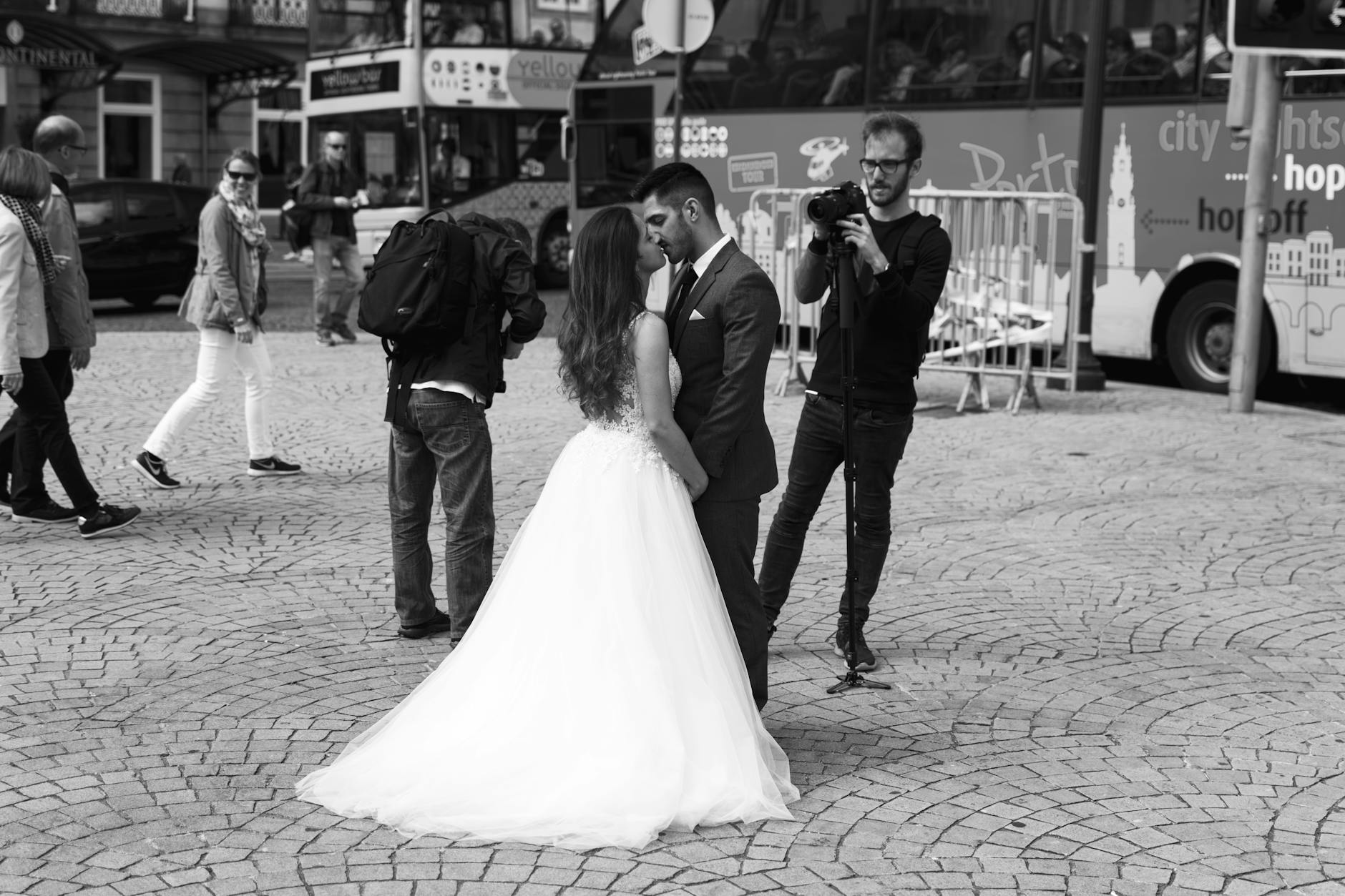 Black and white photo of a bride and groom embracing on a busy city street.