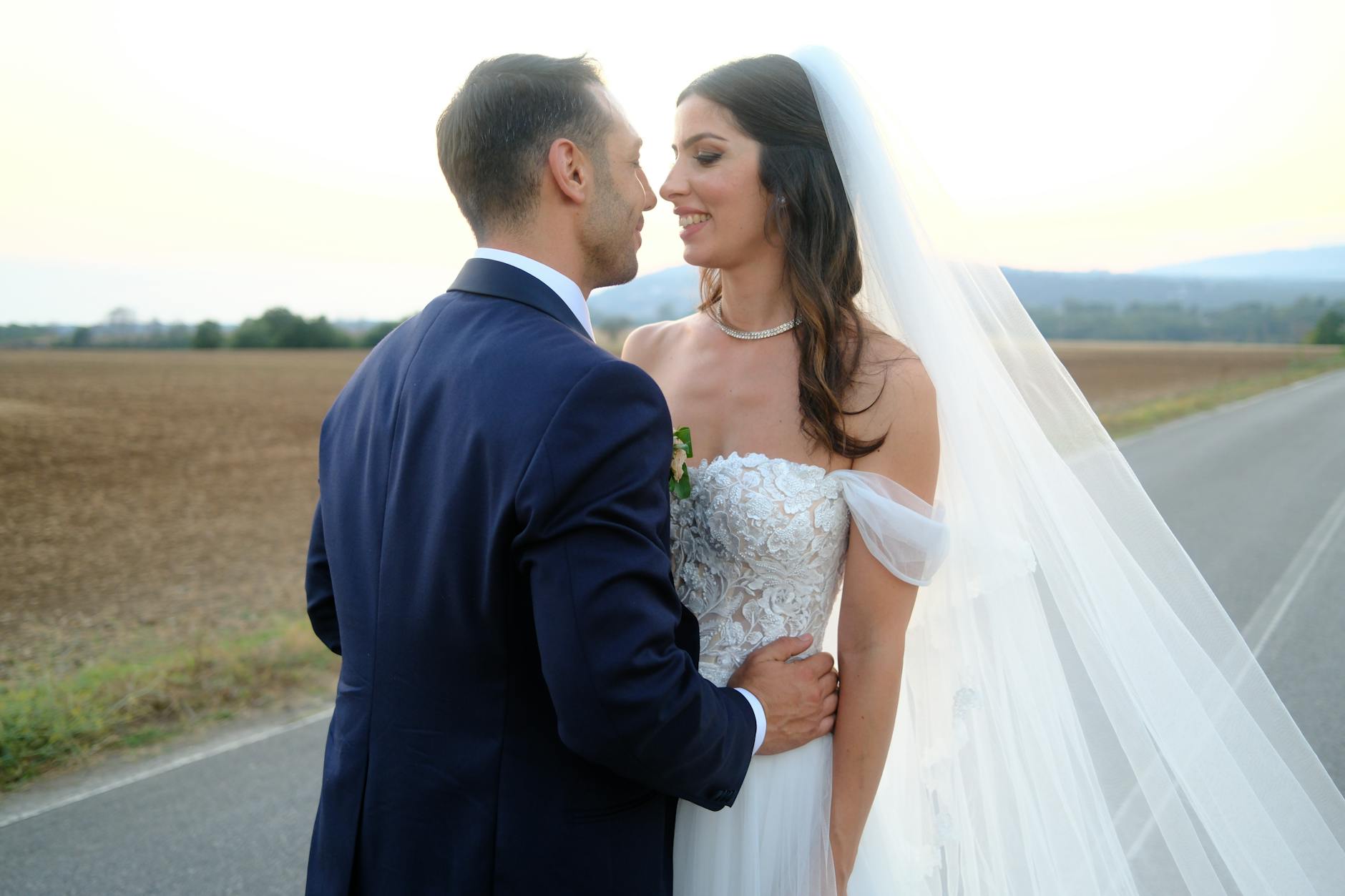 A loving couple shares a tender moment outdoors during their wedding day, captured beautifully at dusk.