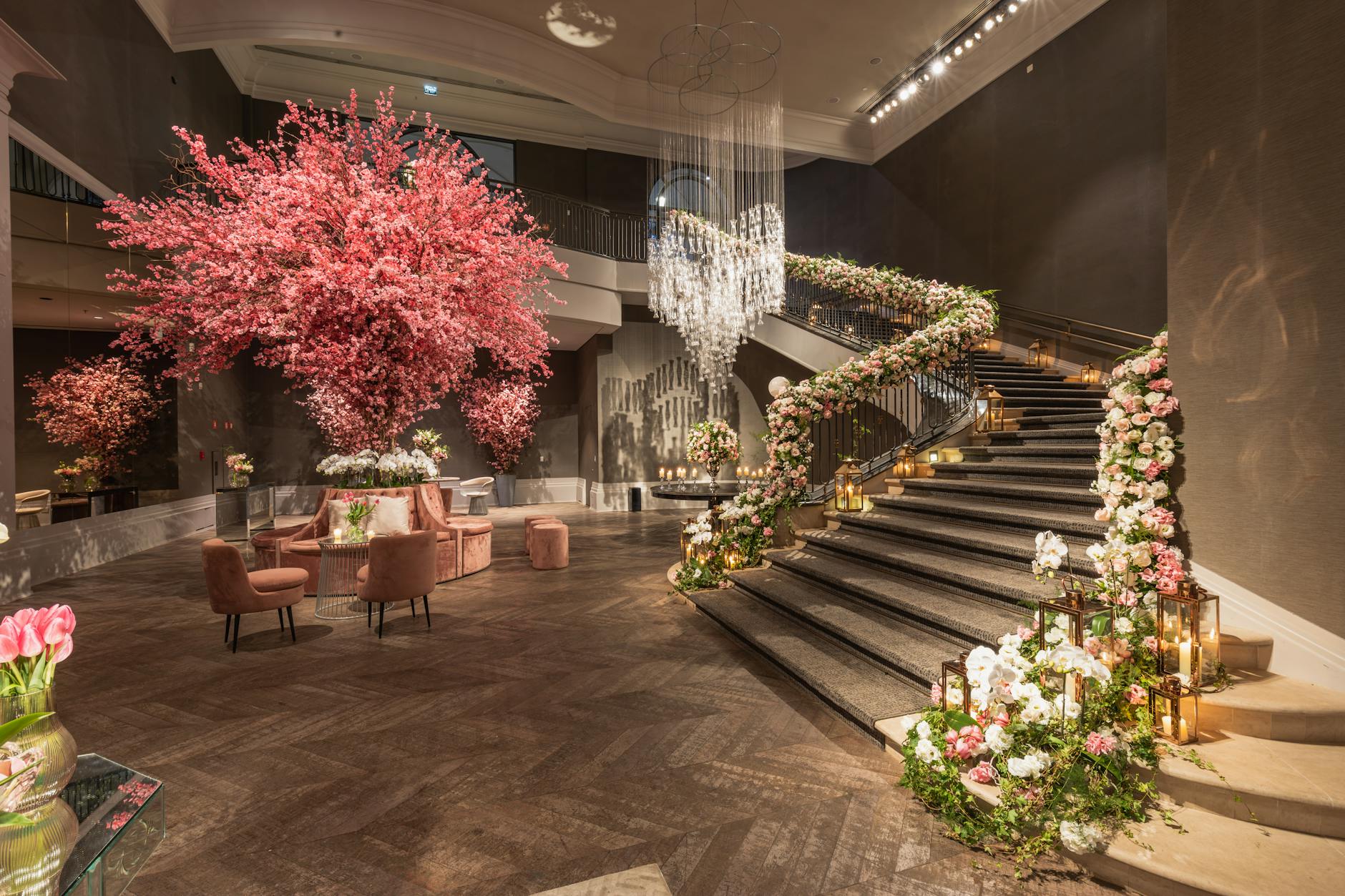 A grand hotel lobby with exquisite floral decorations, spiral staircase, and elegant chandeliers.