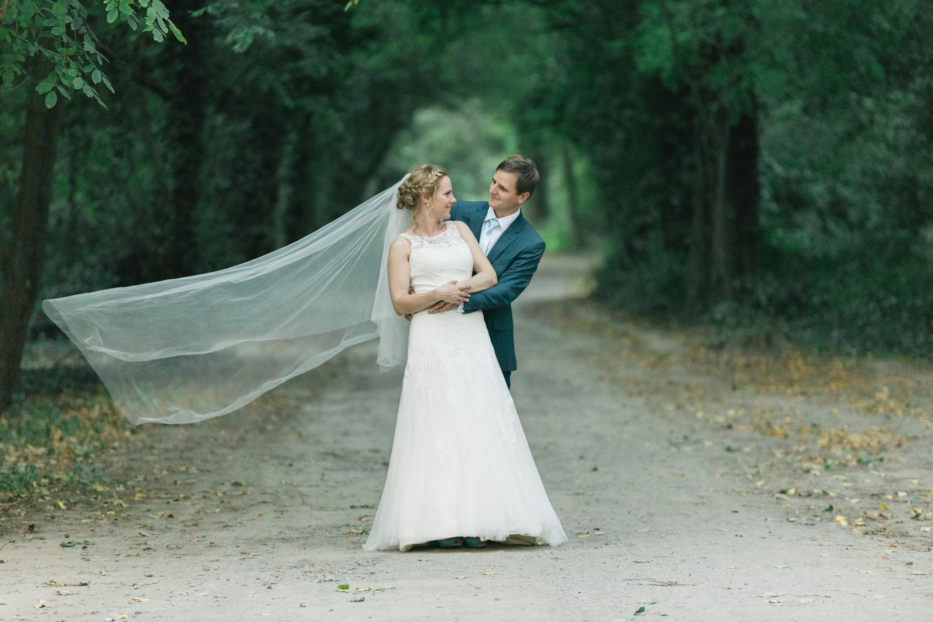 Bride and groom embrace on a forest path, capturing a magical wedding moment.