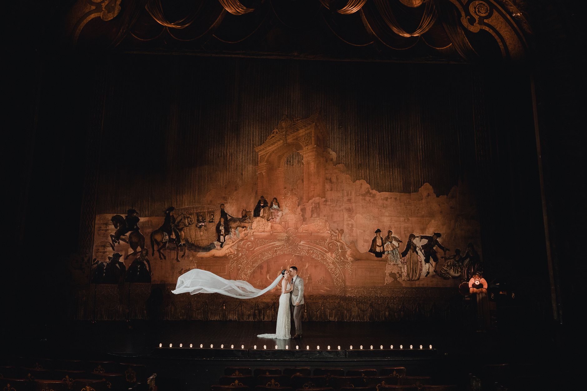 A couple shares a romantic moment on a grand theater stage in Los Angeles.