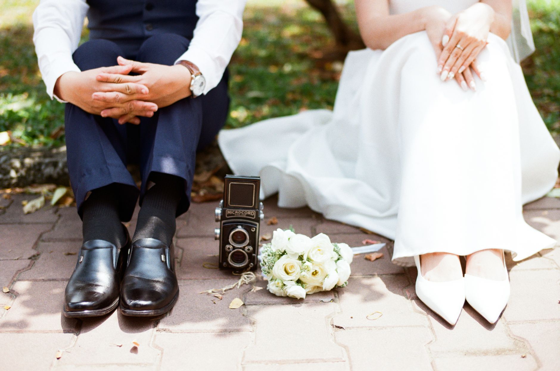 Charming wedding scene with vintage camera and couple on pavement, capturing a timeless moment.