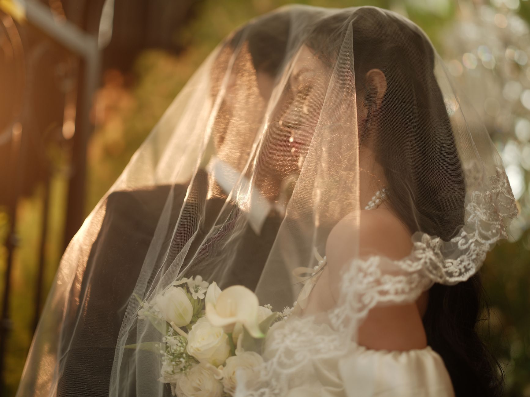 Bride and groom sharing an intimate moment under a veil in a garden in Hà Nội, Vietnam.