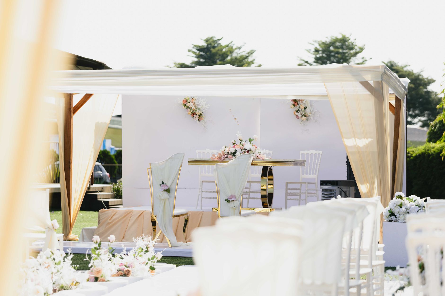 Beautiful outdoor wedding ceremony setting with white and pastel-colored decor and floral arrangements.