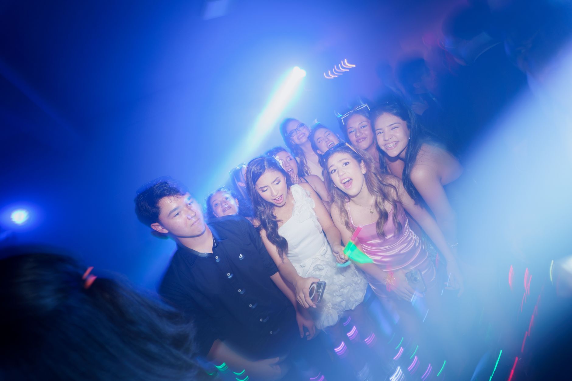 Young adults enjoying a vibrant party at a nightclub under colorful lights.
