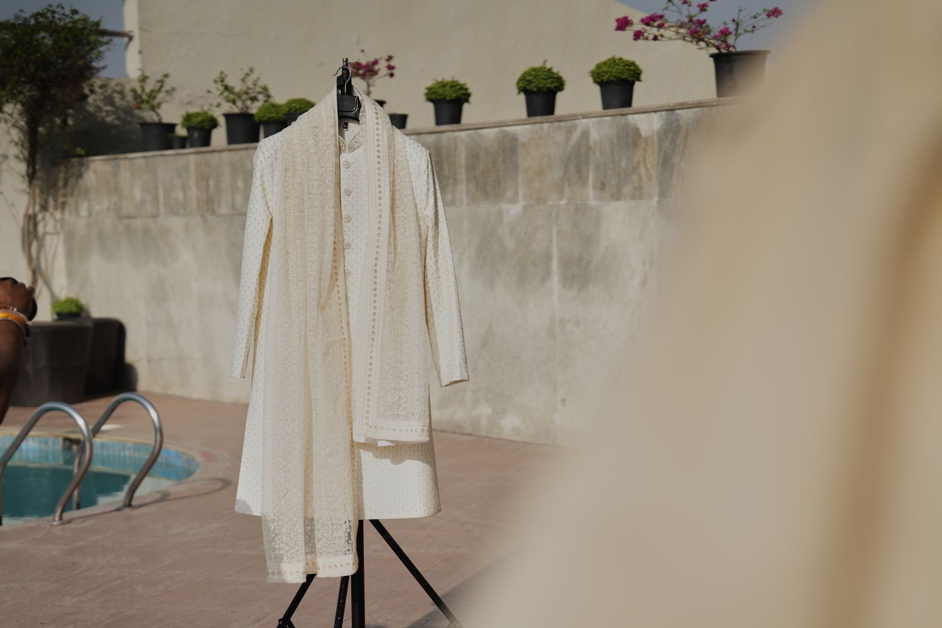Stylish cream sherwani on display outdoors by a pool, perfect for weddings.