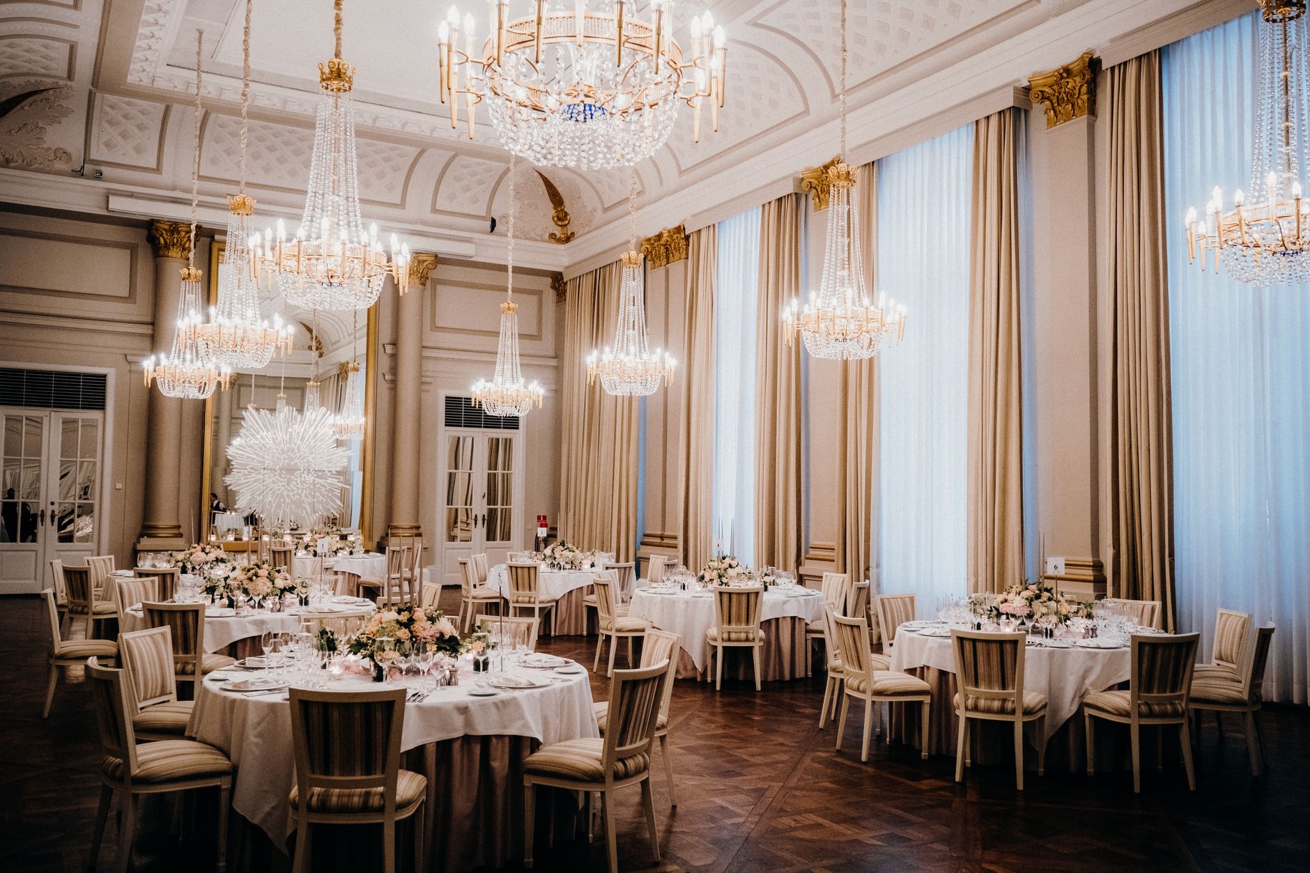 Luxurious ballroom featuring elegant chandeliers and a sophisticated dining arrangement, ideal for events.