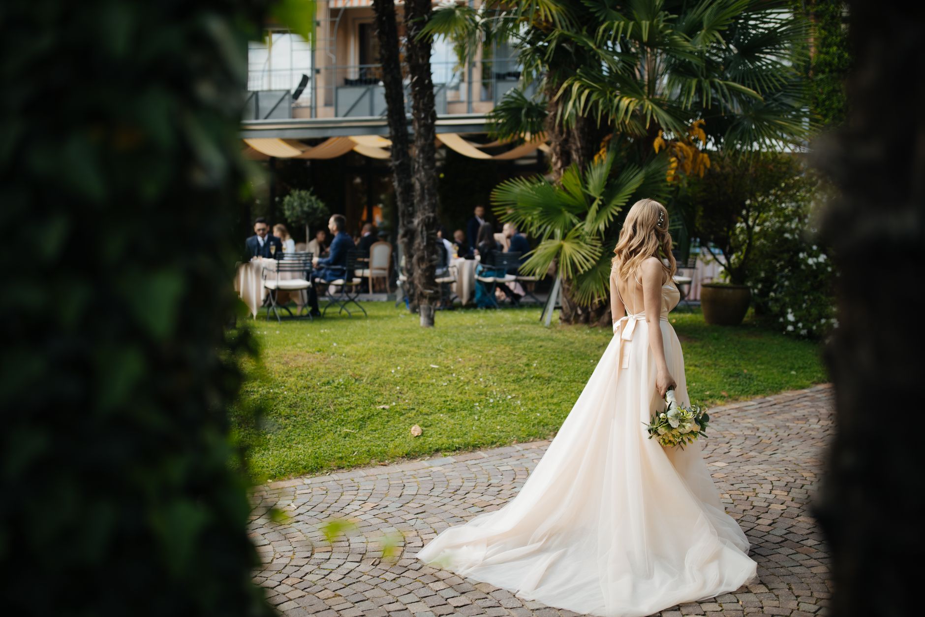 Beautiful bride in gown walking in lush garden setting during outdoor wedding in Lugano.