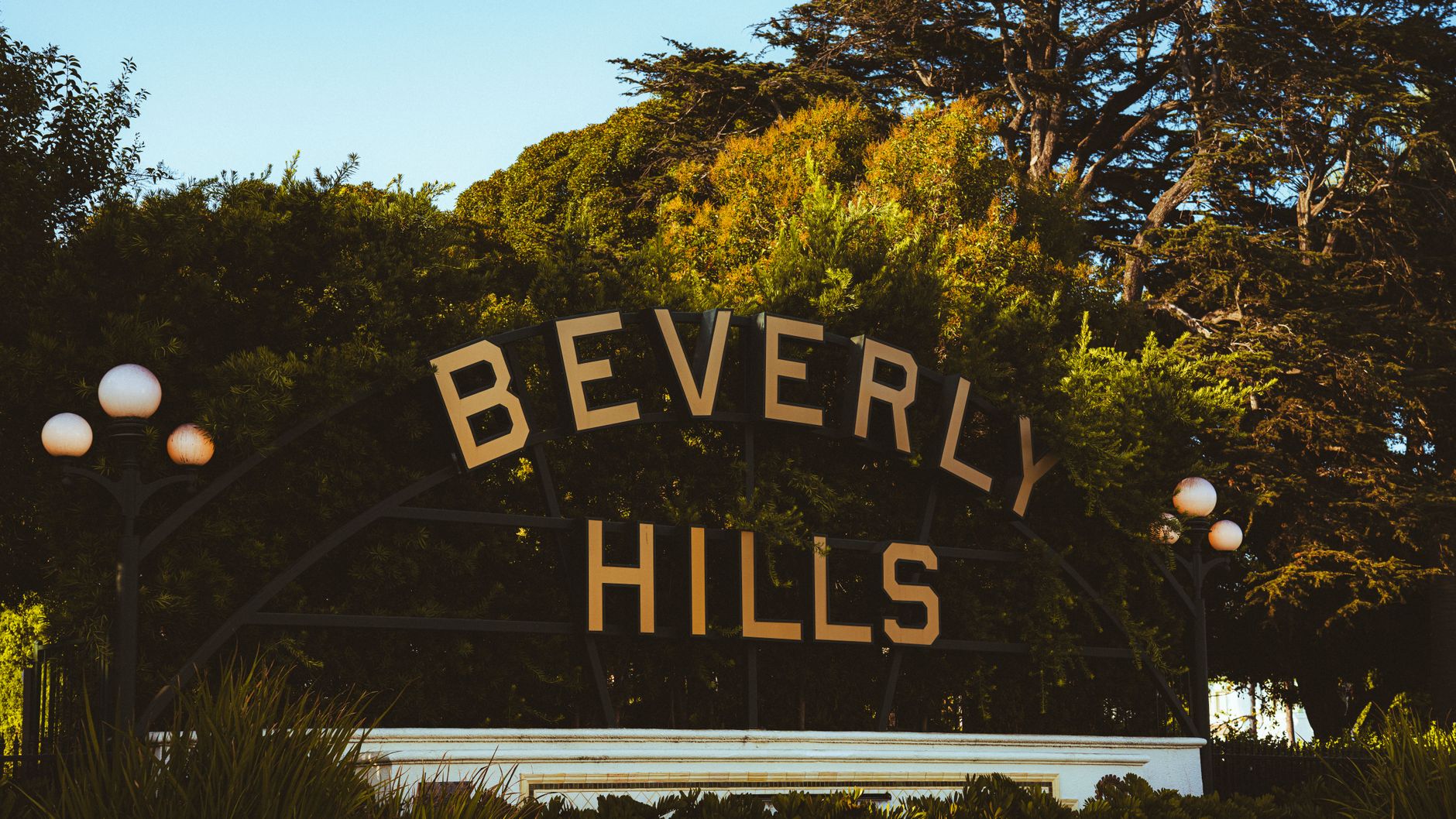 Discover the famous Beverly Hills sign amid lush greenery on a sunny day.