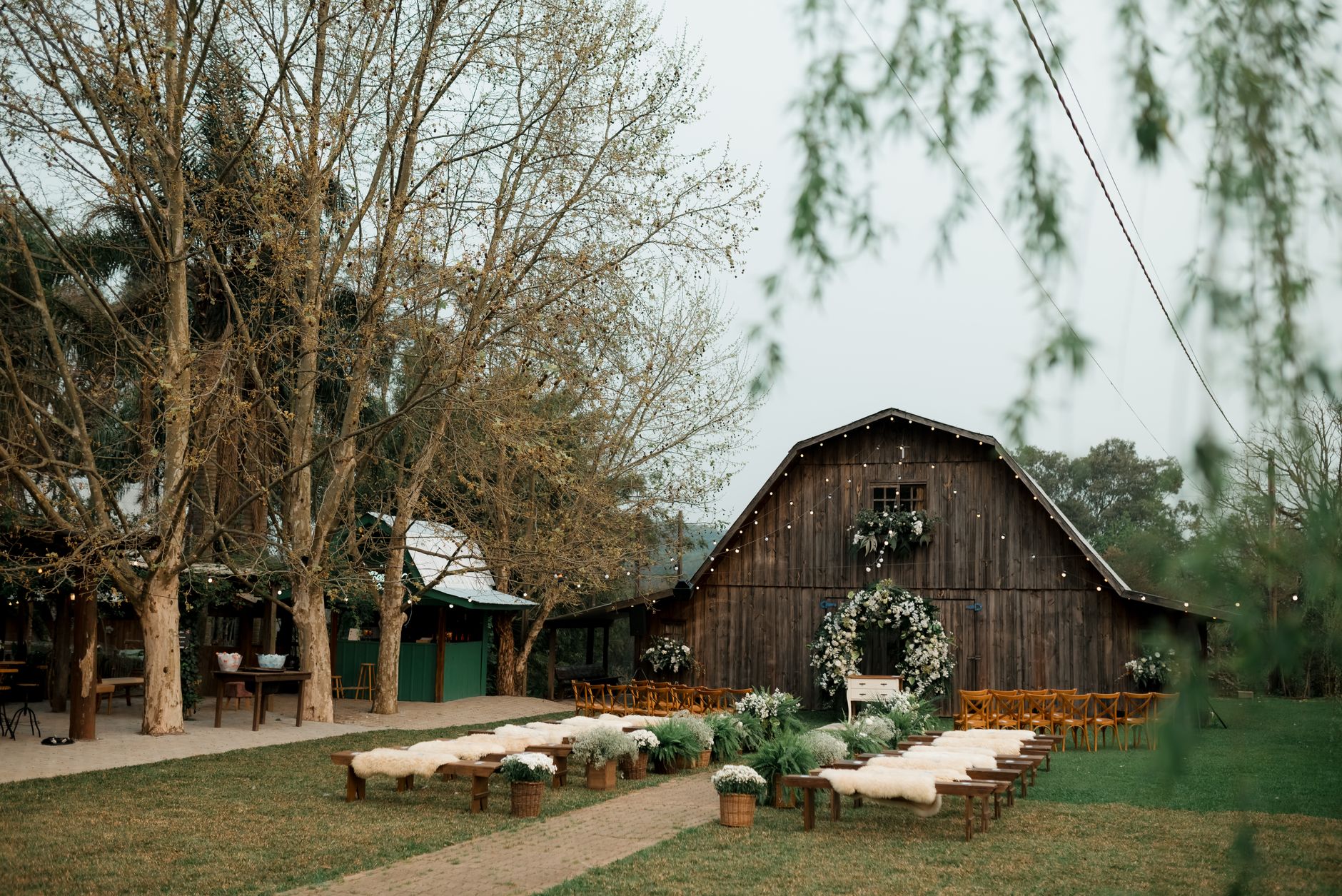 Rustic barn decorated for an outdoor wedding ceremony with floral arrangements.