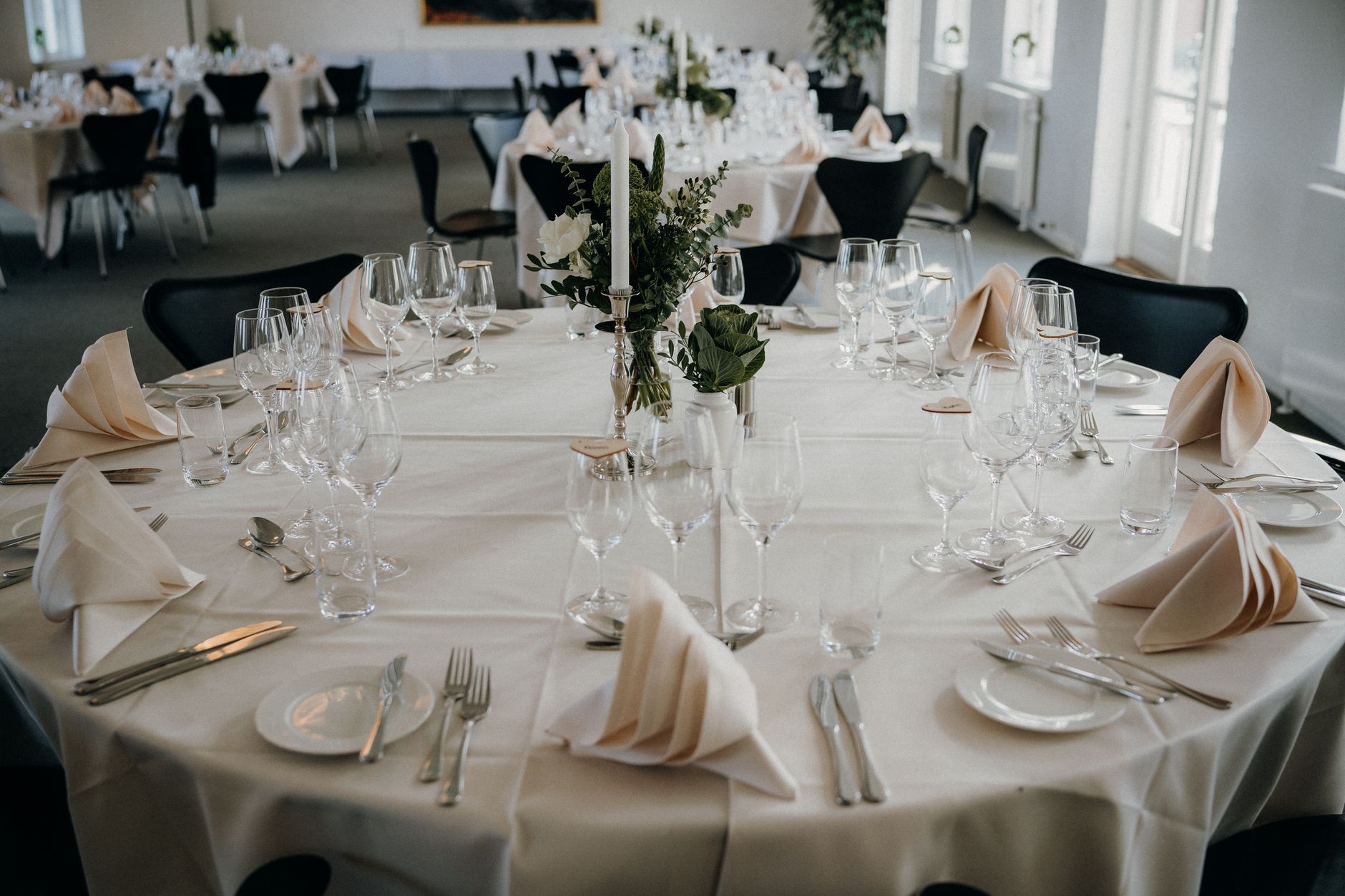 A beautifully arranged dining table setup for a wedding reception with elegant tableware and floral centerpiece.