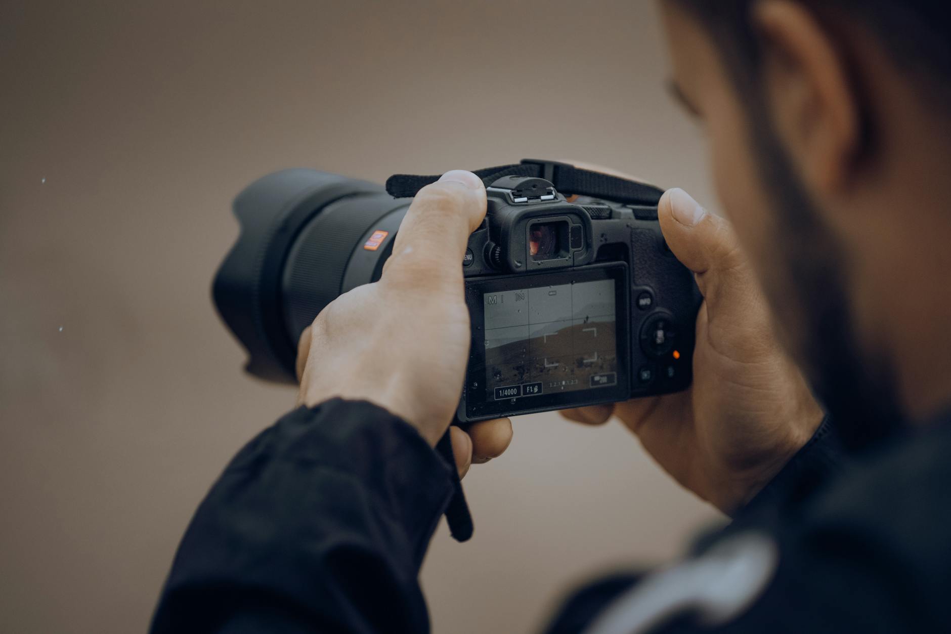 Detailed shot of a photographer adjusting settings on a digital camera outdoors.