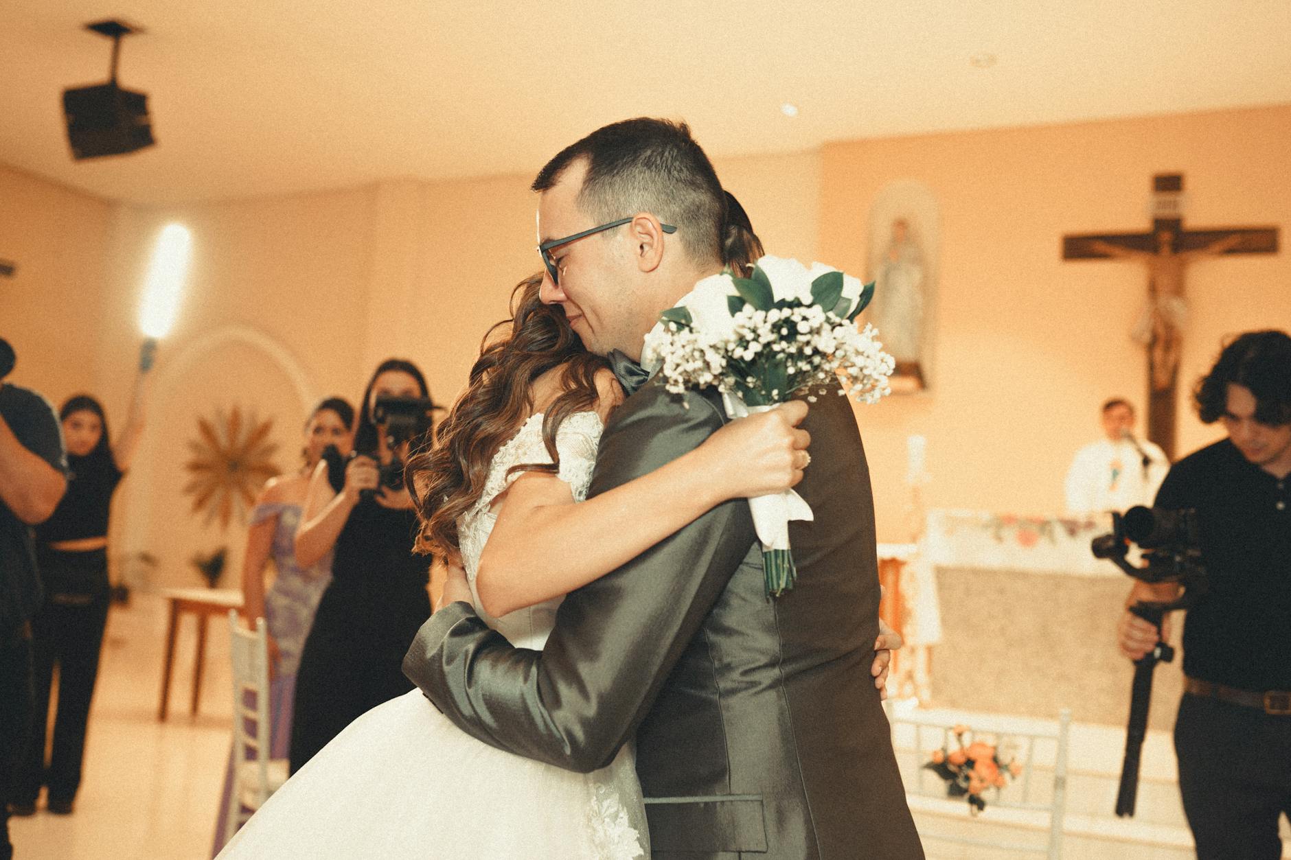 A loving embrace between bride and groom at a wedding ceremony in a chapel.