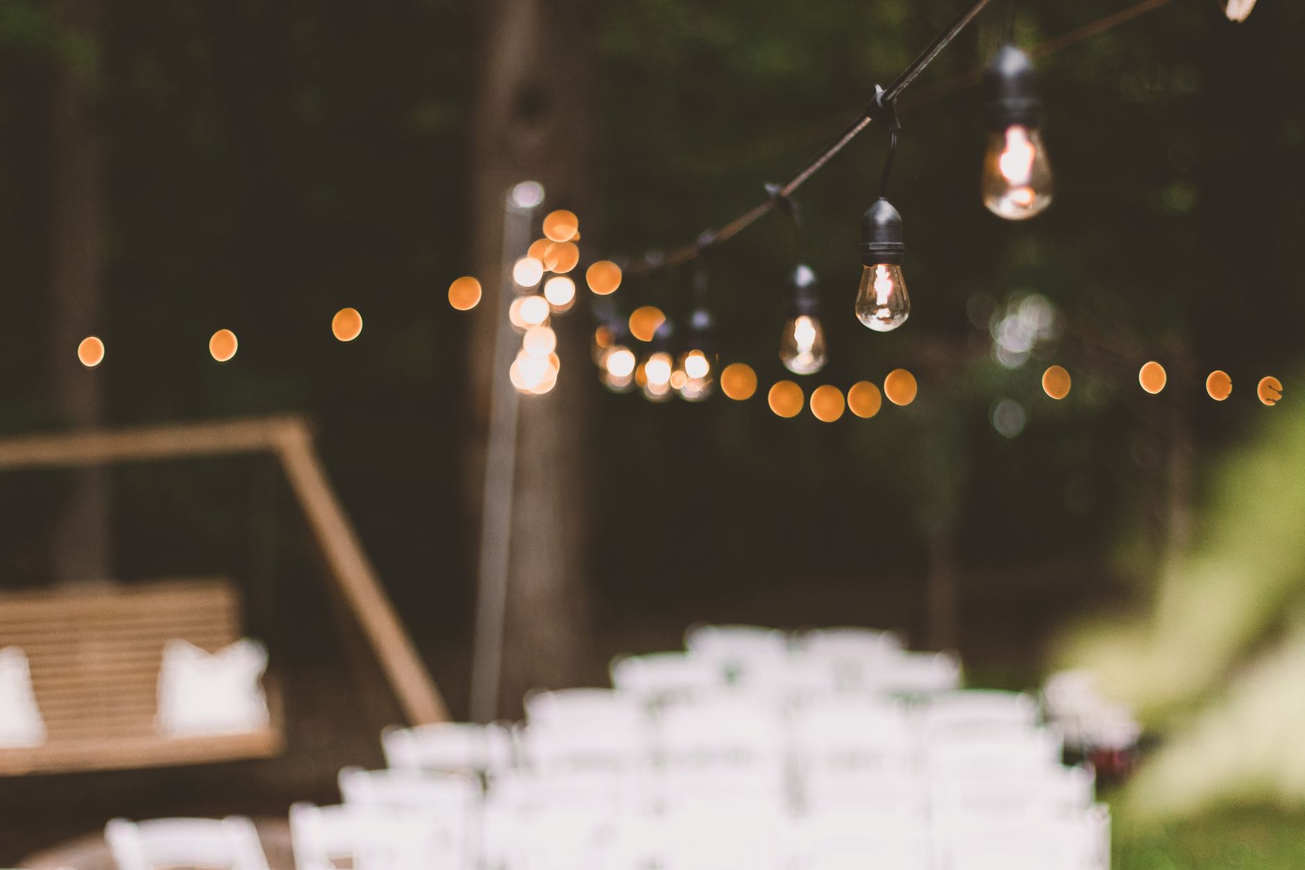 Warm and cozy string lights illuminating an outdoor garden setting at dusk, creating a festive ambiance.