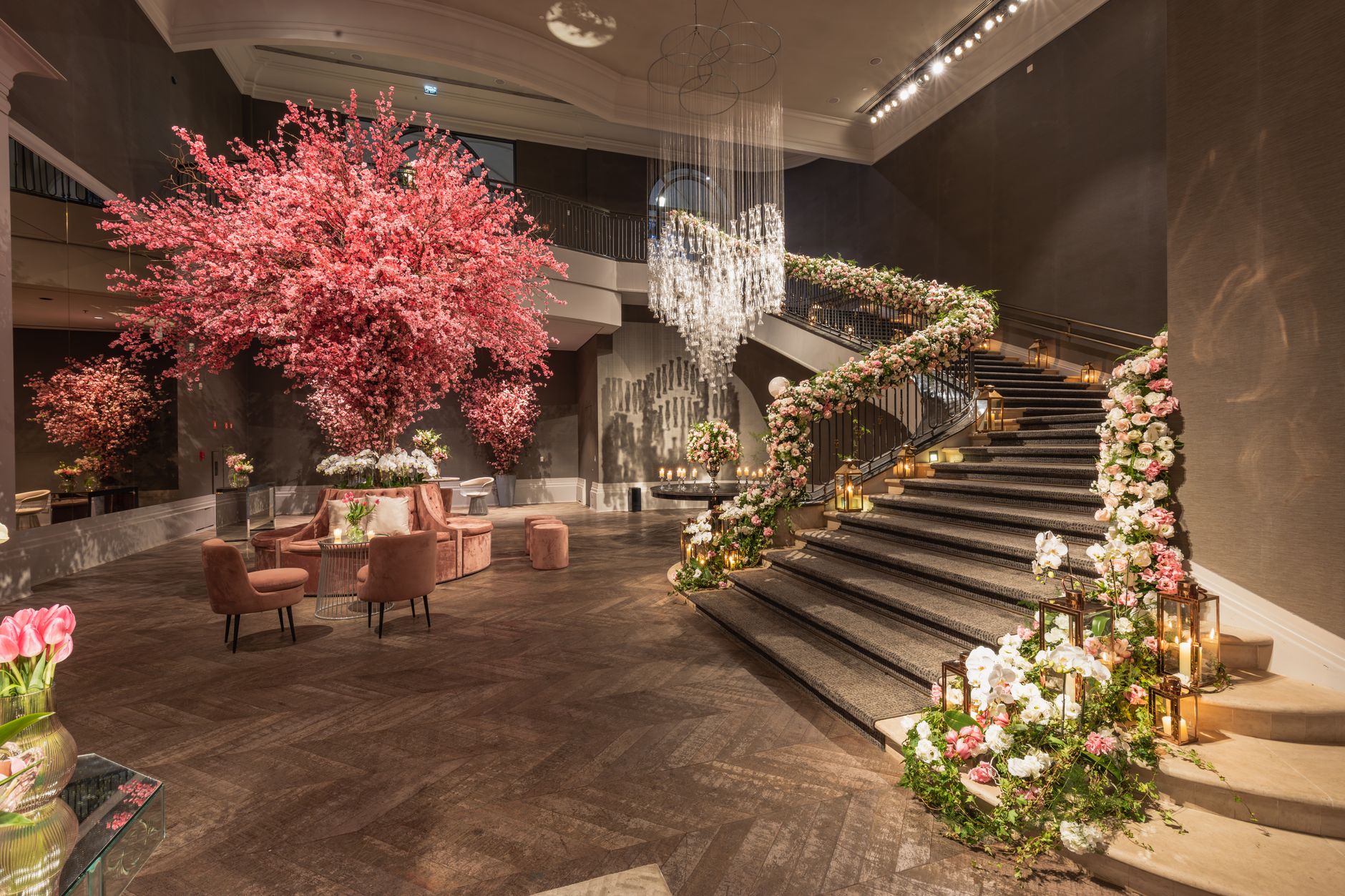 A grand hotel lobby with exquisite floral decorations, spiral staircase, and elegant chandeliers.