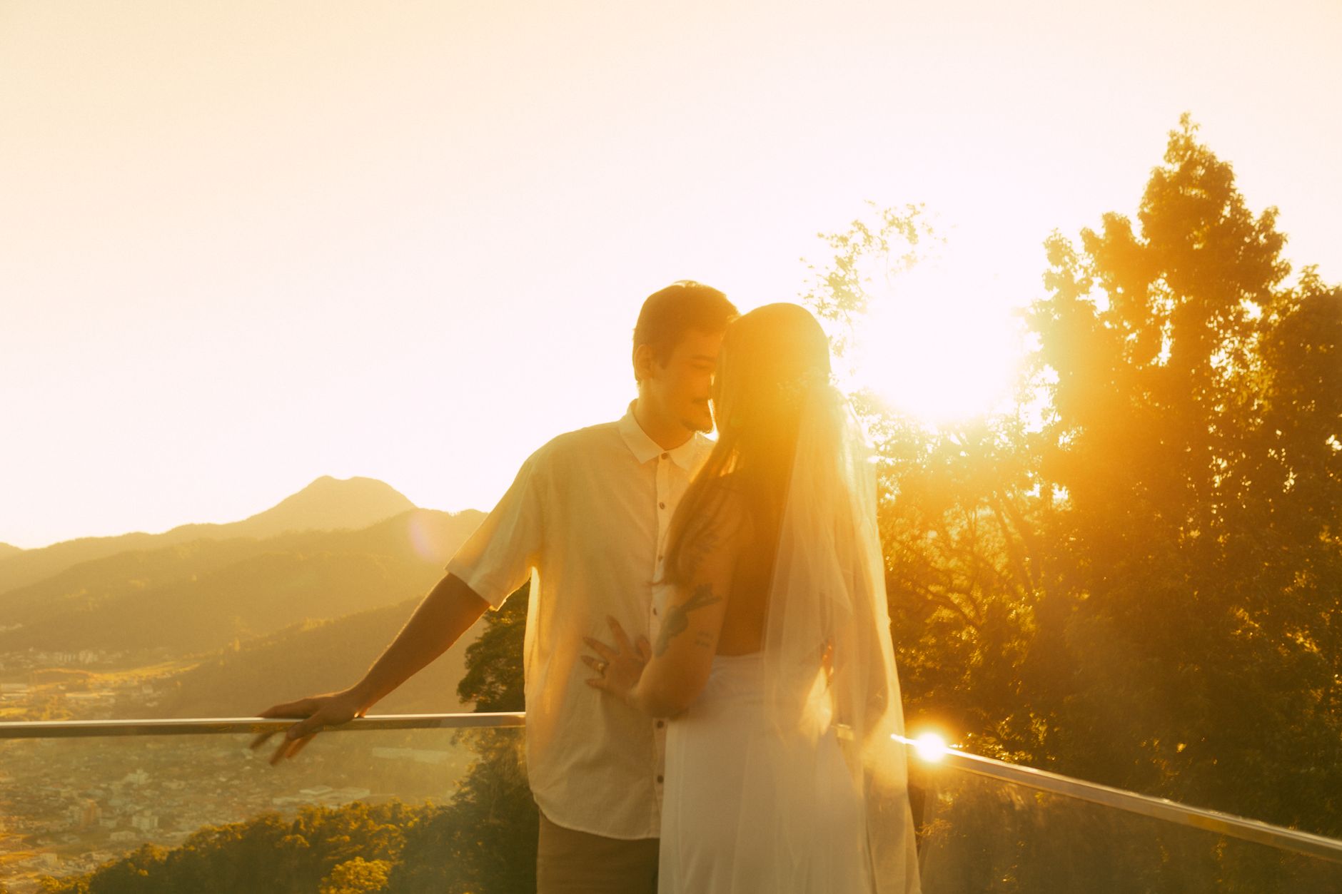 Newlywed couple embracing at sunset on a balcony, capturing a romantic moment.