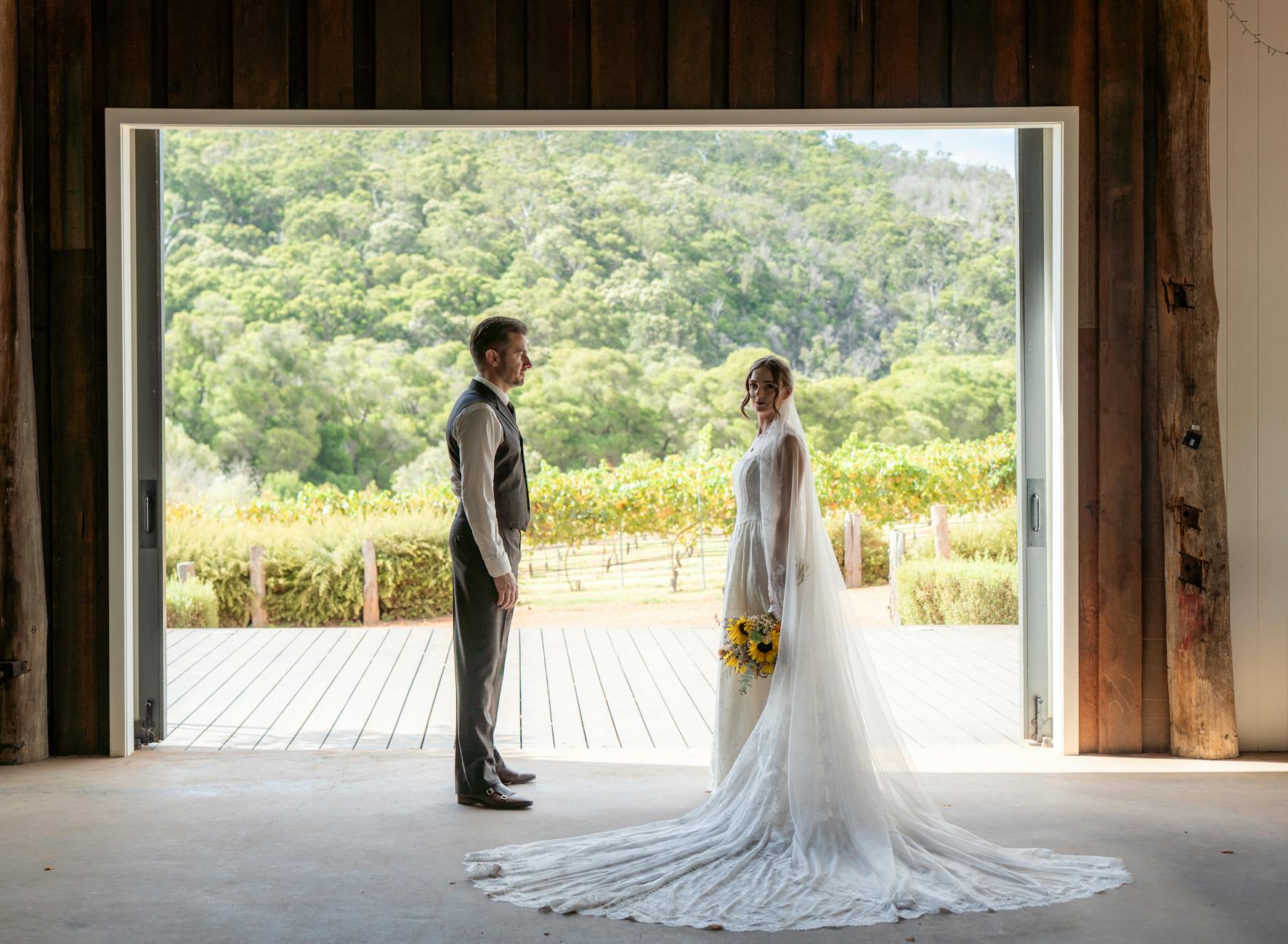 A bride and groom stand in a vineyard doorway, capturing a romantic rustic wedding moment.