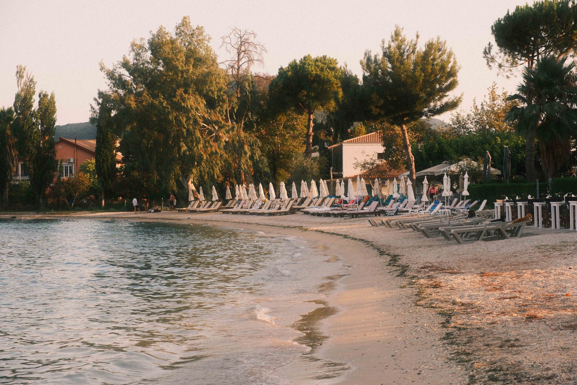 Peaceful beach scene in Lefkada, Greece, with sun loungers and soft evening light.