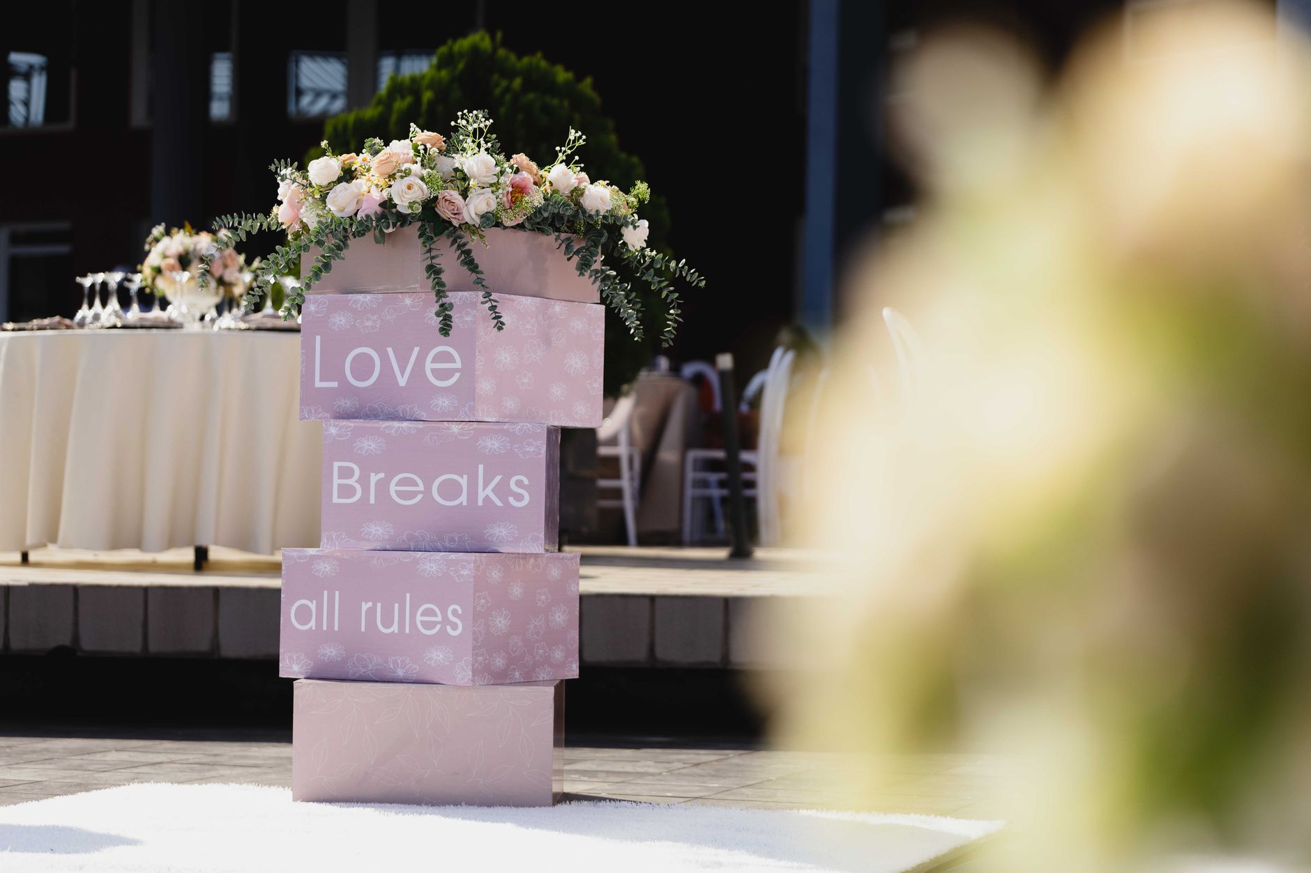 Outdoor wedding setting with floral decorations and "Love Breaks all rules" signage.