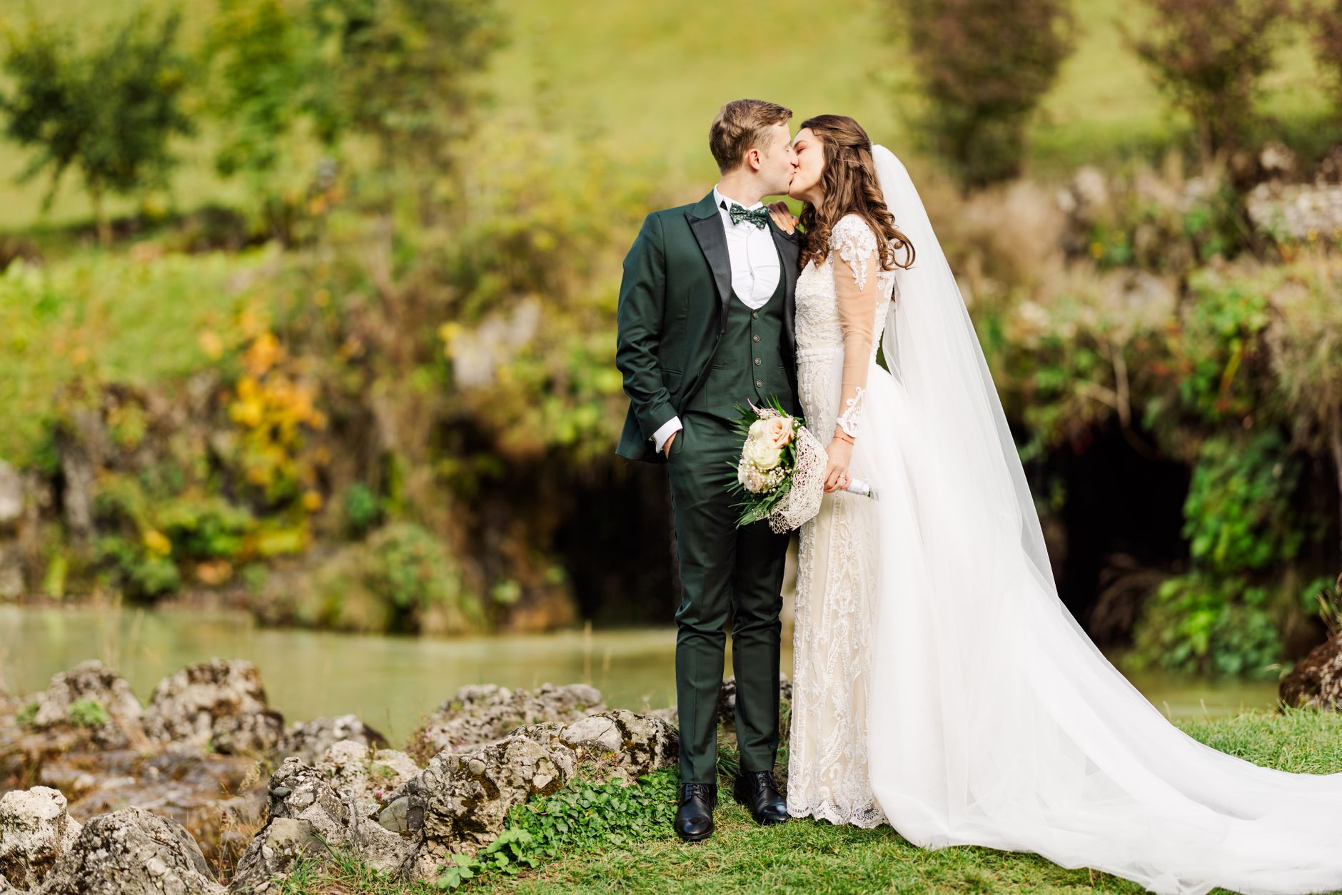 Bride and groom share a romantic kiss in lush Bușteni, Romania garden setting.