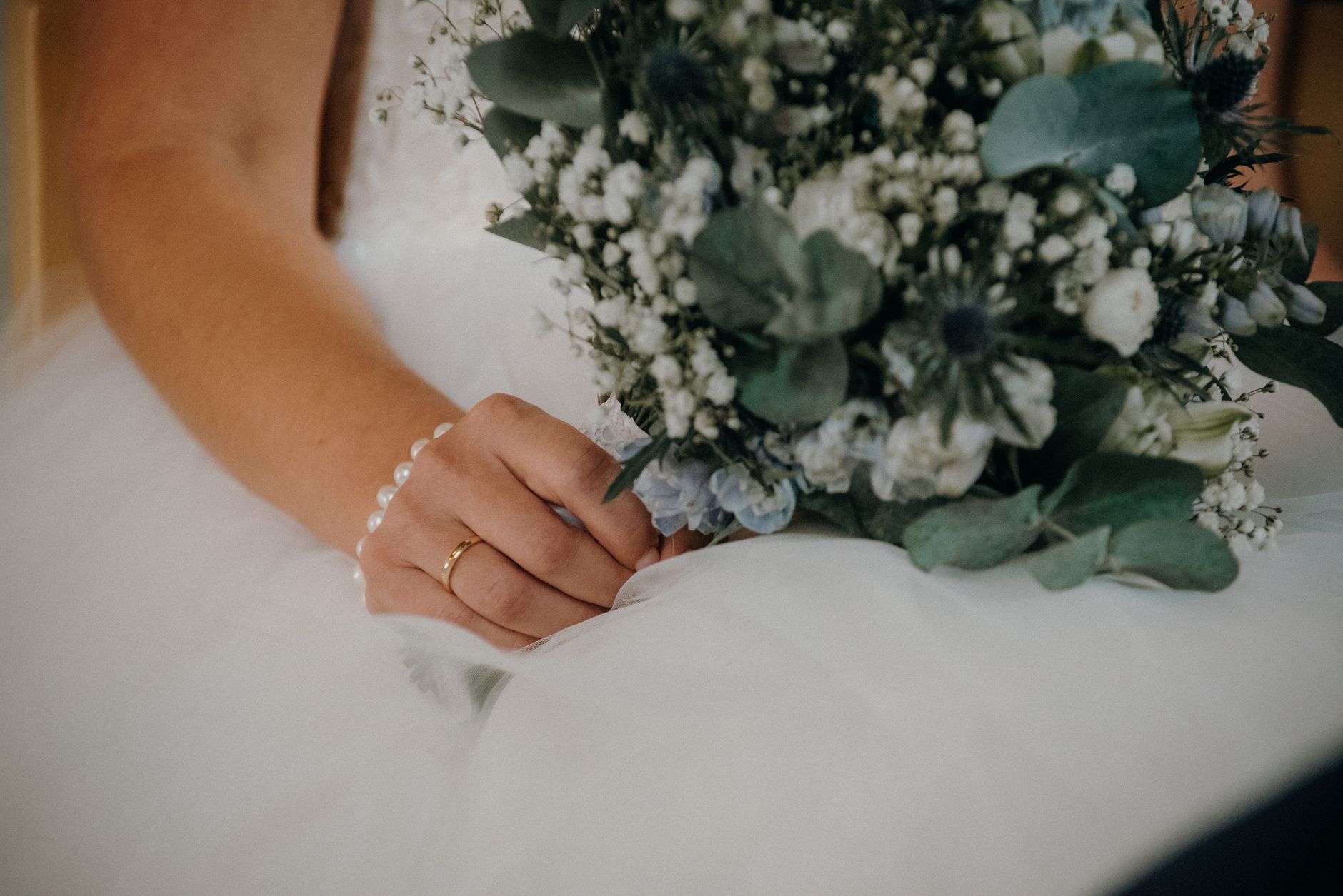 Close-up of a bride holding a lush bouquet, showcasing wedding elegance and floral beauty.