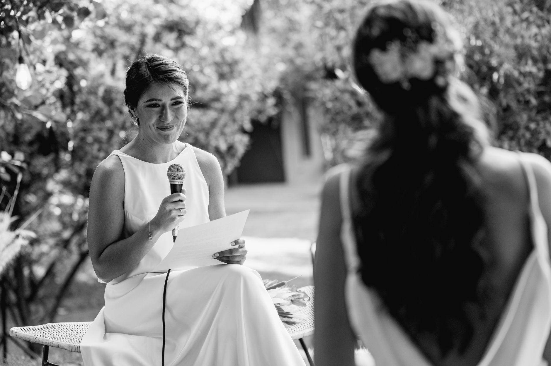 Elegant wedding speech scene with bridesmaid and bride outdoors.
