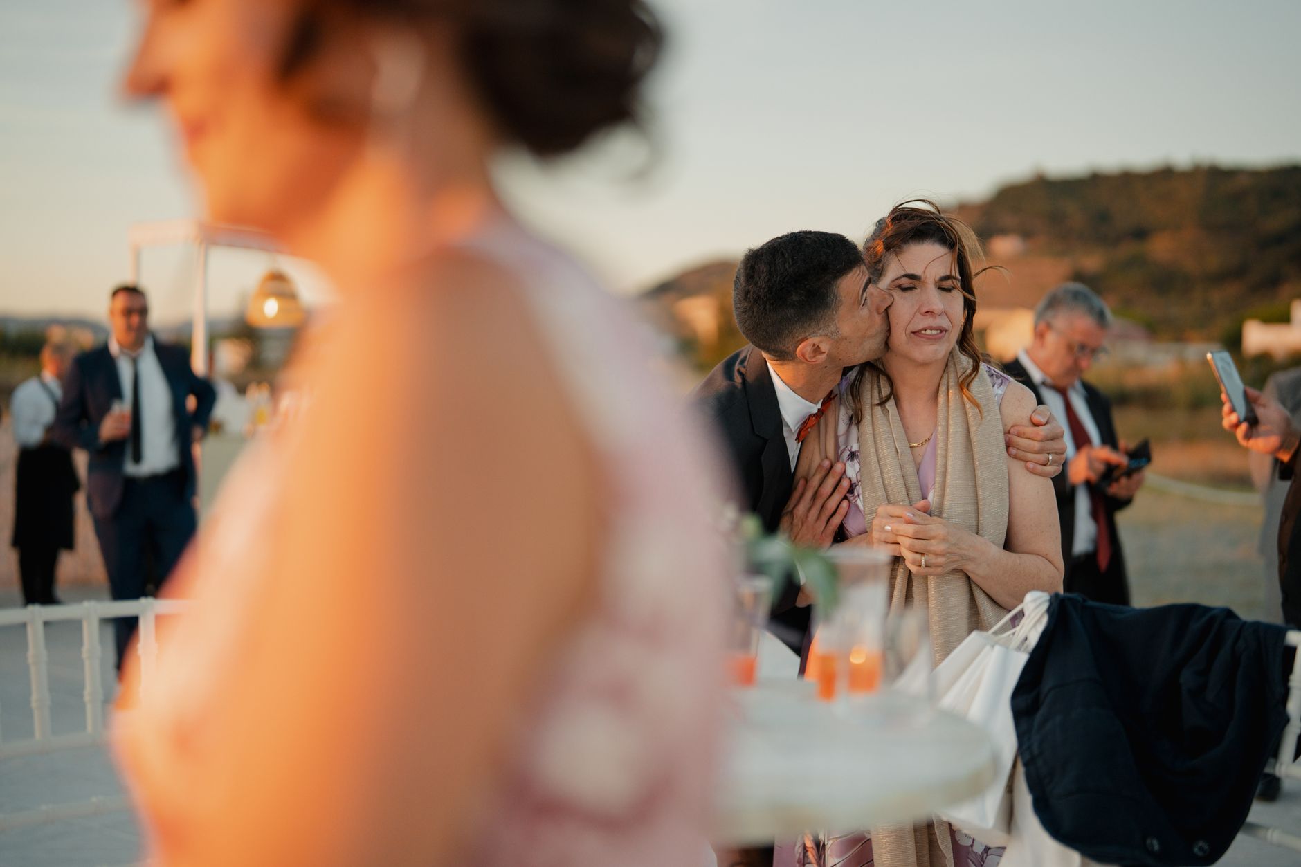 Candid moment at an outdoor wedding reception during sunset, capturing heartfelt emotions and interactions.