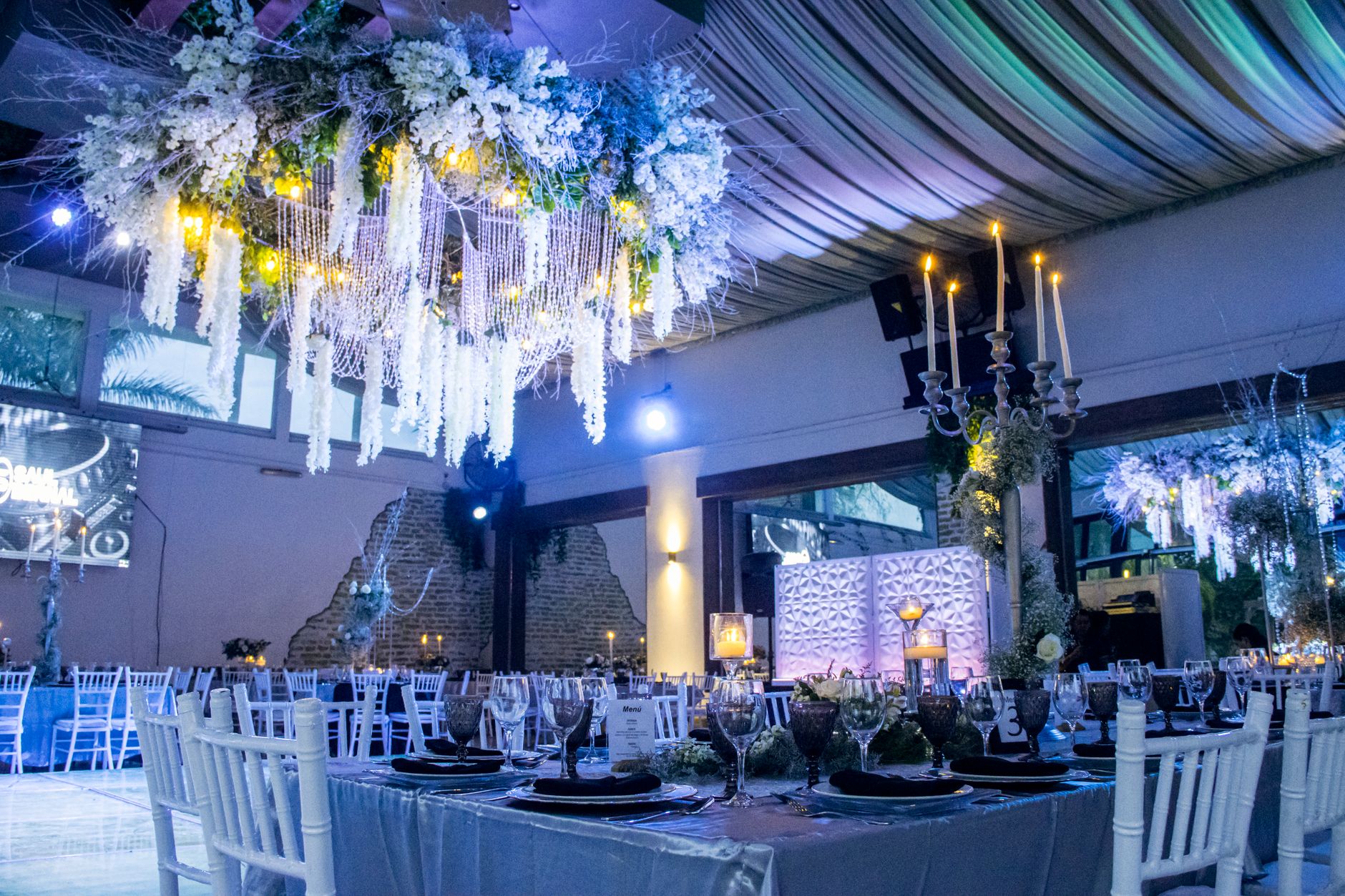 Luxurious indoor wedding venue in León, México featuring an exquisite floral chandelier and elegant table settings.