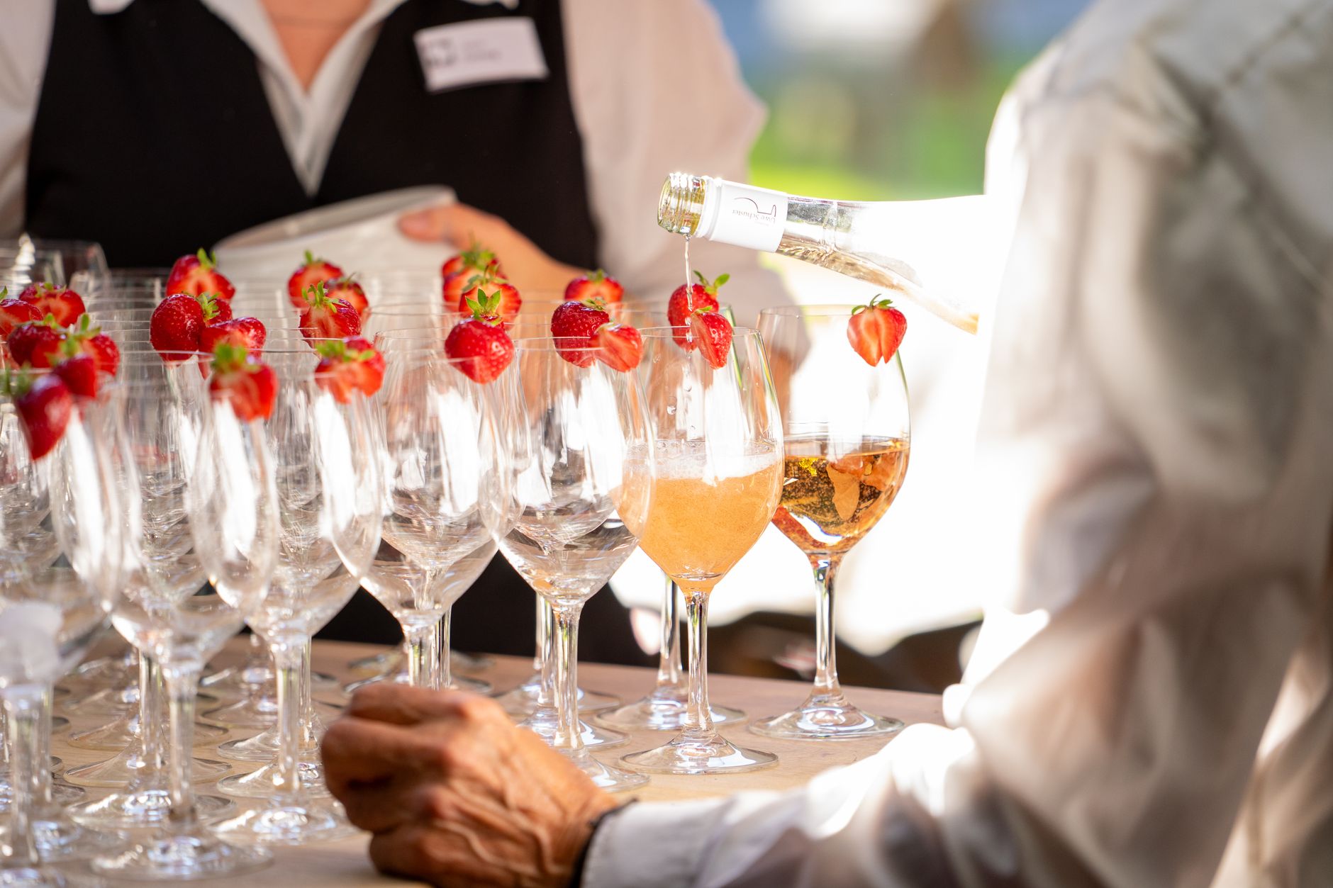 Elegant event with glasses of champagne and strawberries, expertly poured by waiter.
