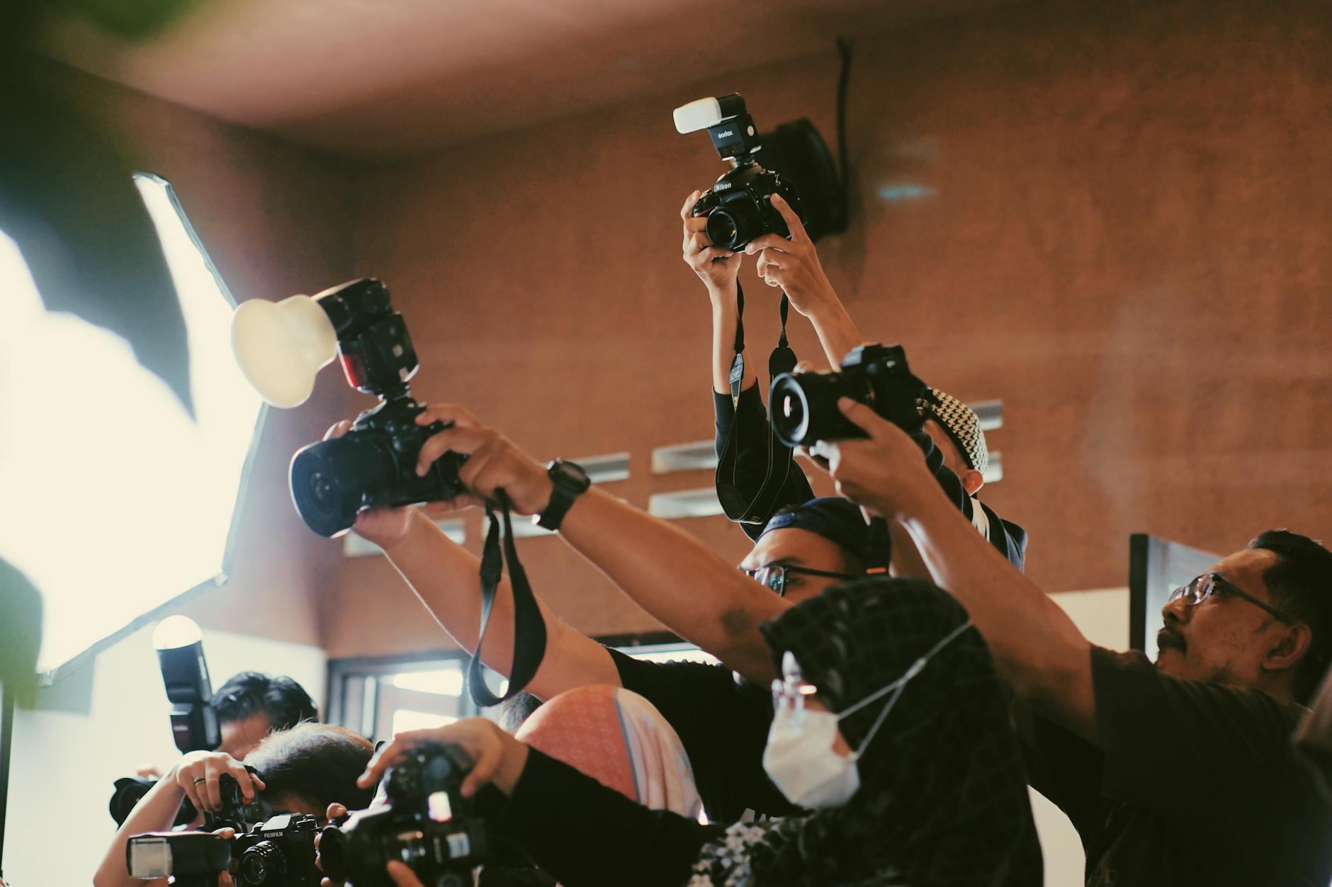 A dynamic gathering of photographers capturing moments indoors with flash.