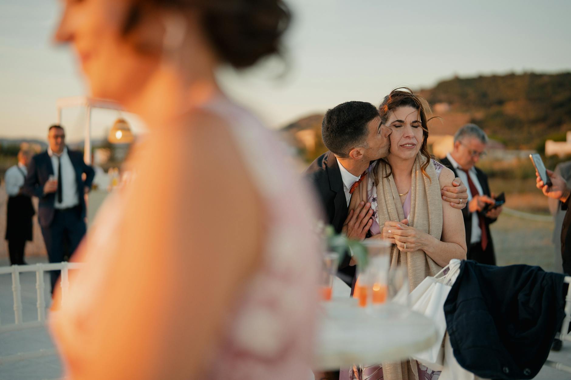 Candid moment at an outdoor wedding reception during sunset, capturing heartfelt emotions and interactions.