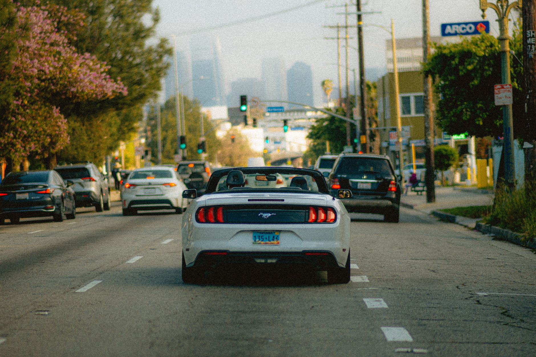 White convertible car on a busy Los Angeles street with a city skyline in the background.