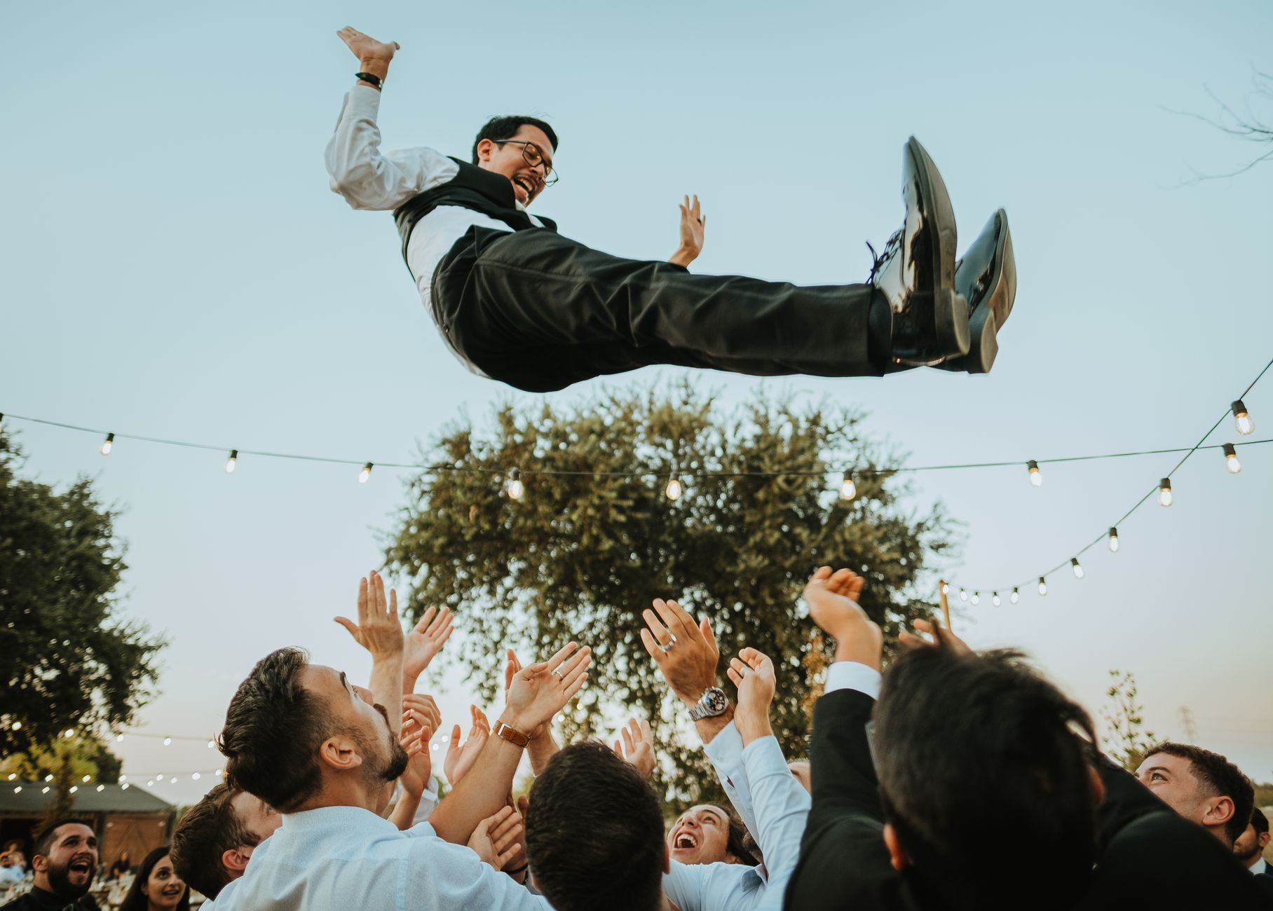 Groom lifted in joyous celebration at an outdoor wedding in Woodland, CA.