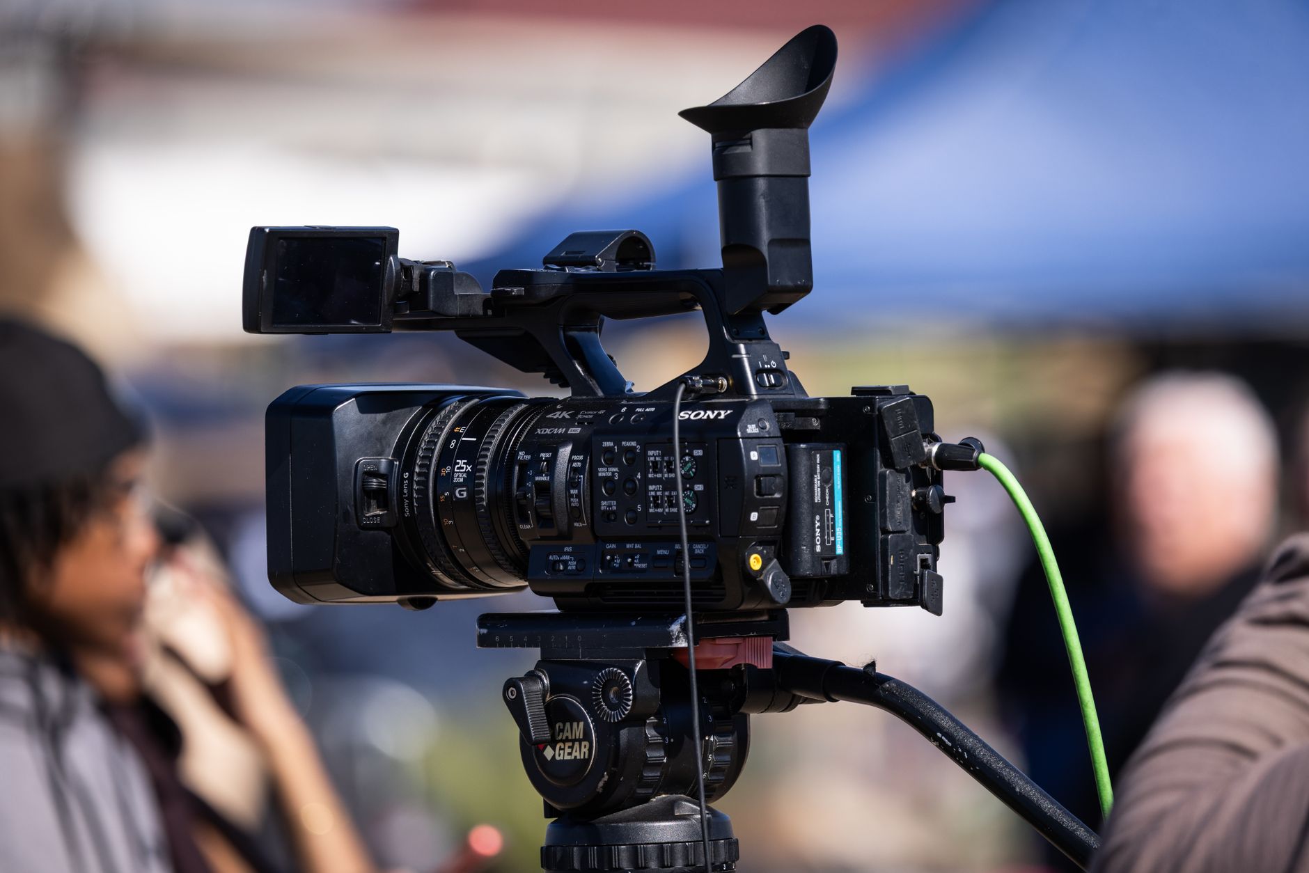 Close-up of a professional video camera set up for filming outdoors, capturing dynamic scenes in natural light.